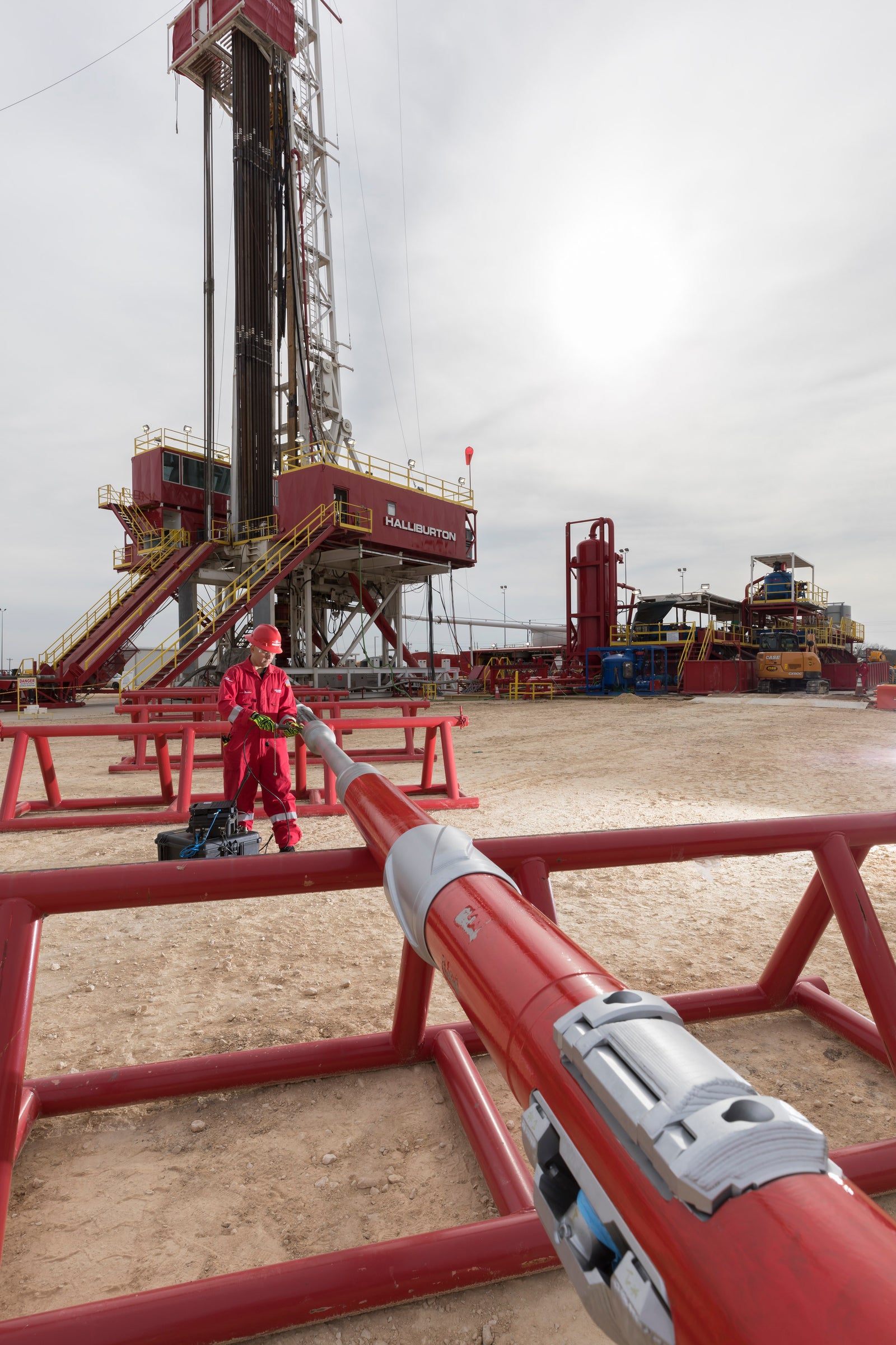 Halliburton engineer in red coveralls working on intelligent rotary steerable system tool at a rigsite