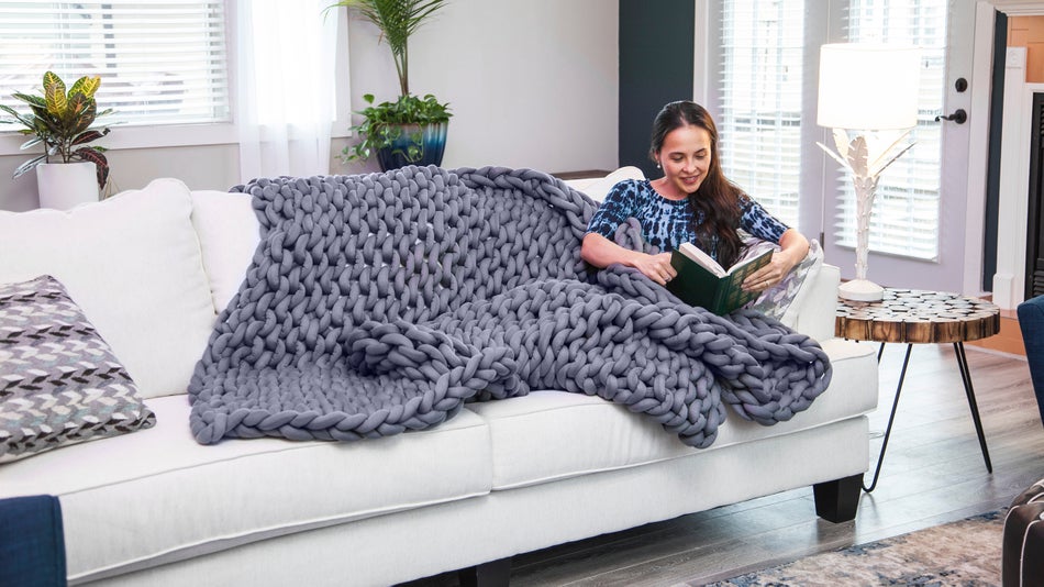 woman reading a book with a weighted blanket on