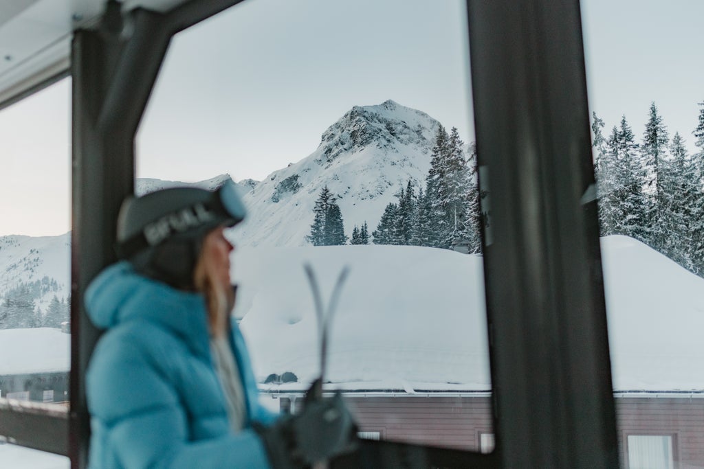Lech Zürs_Woman Admiring Alpine View Indoors_(c): Dominic Kummer - Lech Zürs Tourismus GmbH