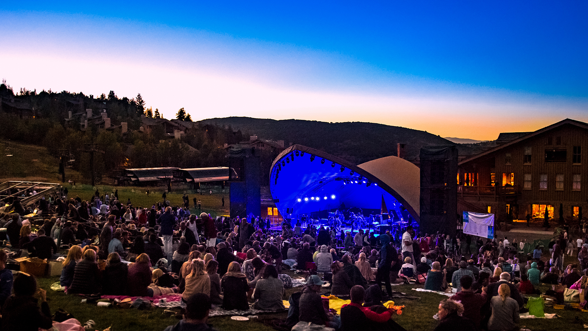 People sitting on lawn at Deer Valley Resort at dusk listening to music