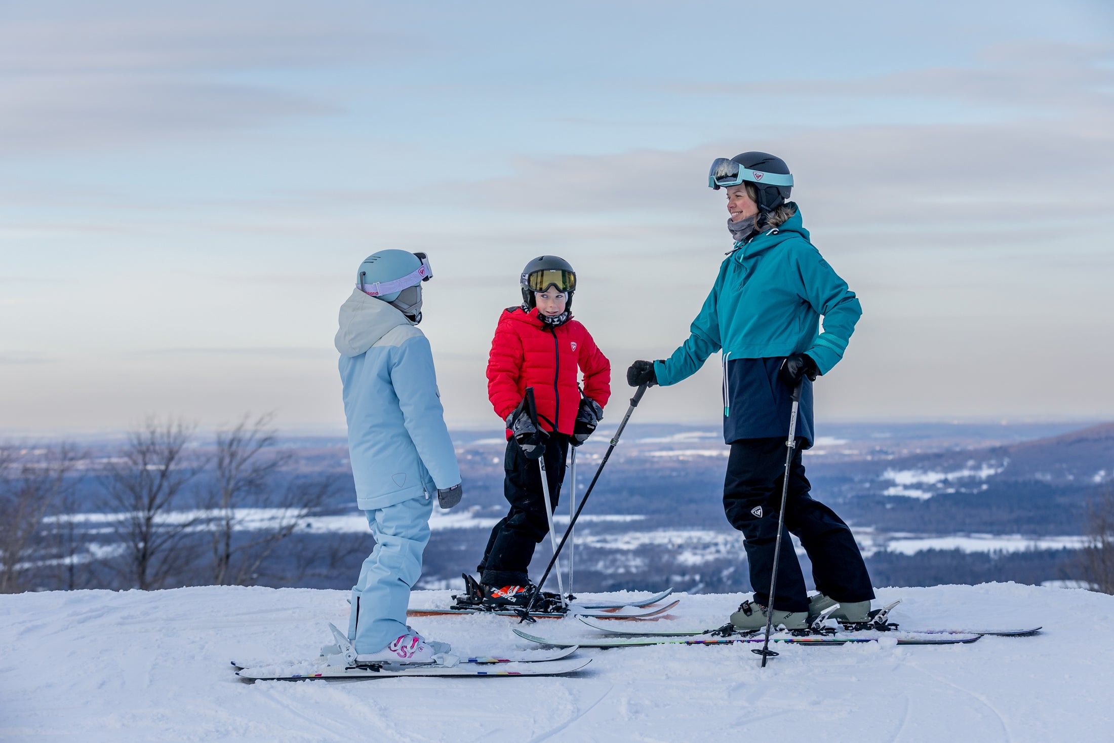 Family taking a break on groomed ski slopes overlooking the valley