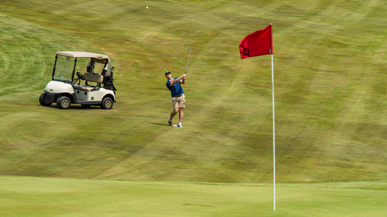 Golfer looking at shot heading toward green