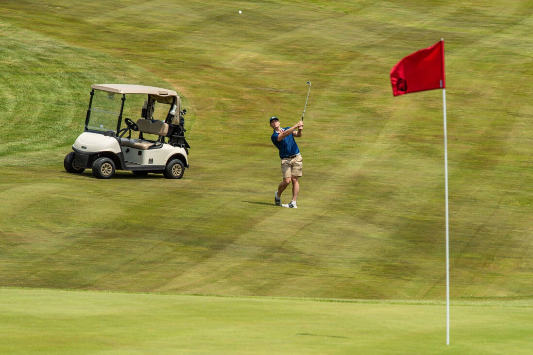 Golfer looking at shot heading toward green