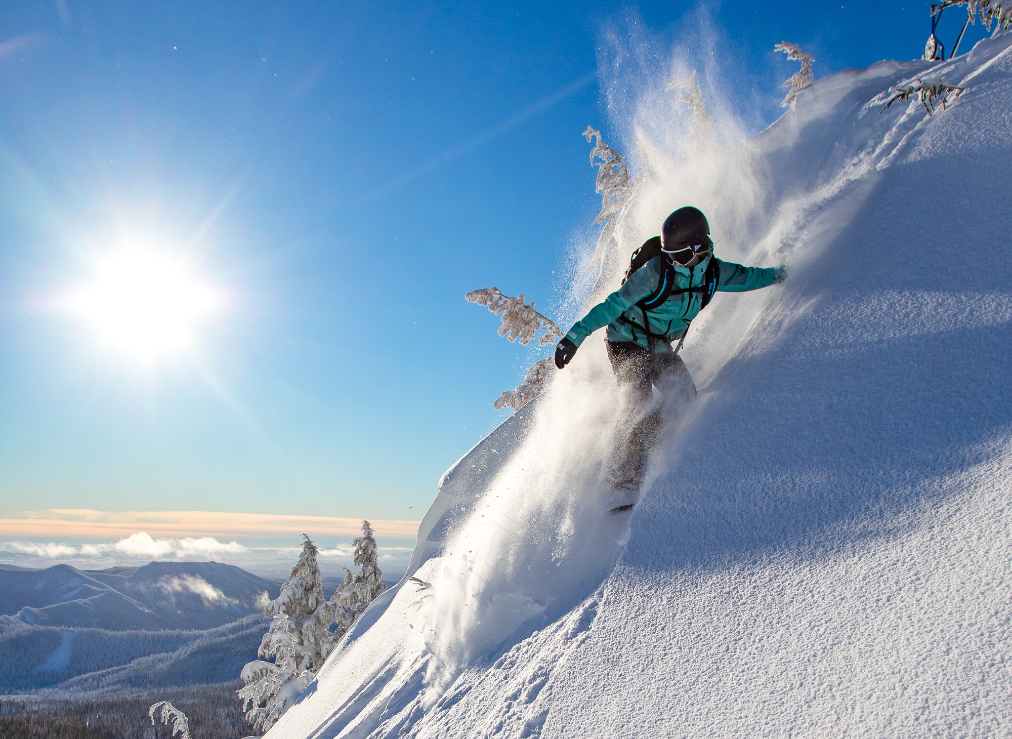 Person skiing down steep run through powder on a sunny day