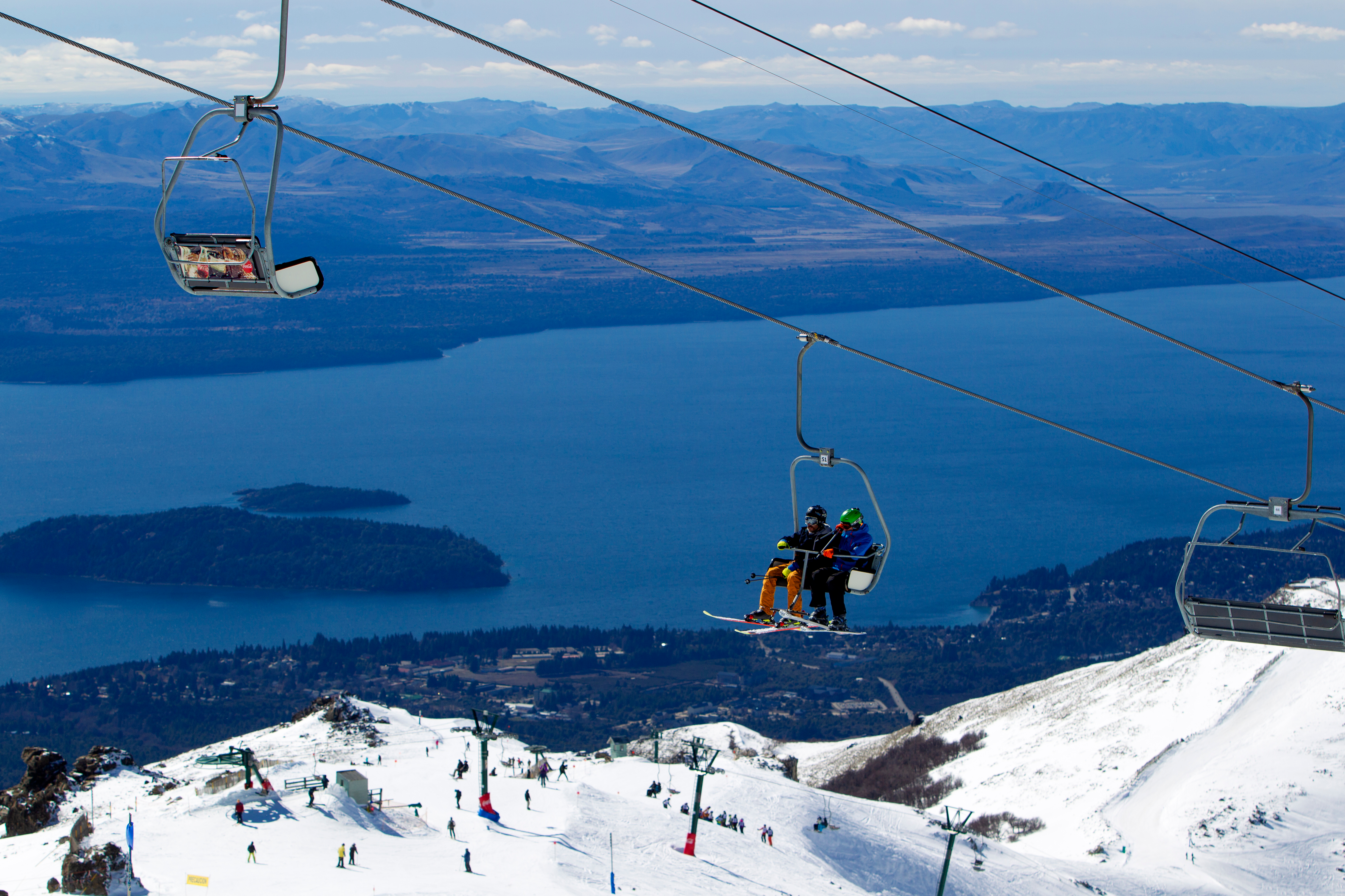 Skiers on chairlift that overlooks lake in Argentina on a clear day