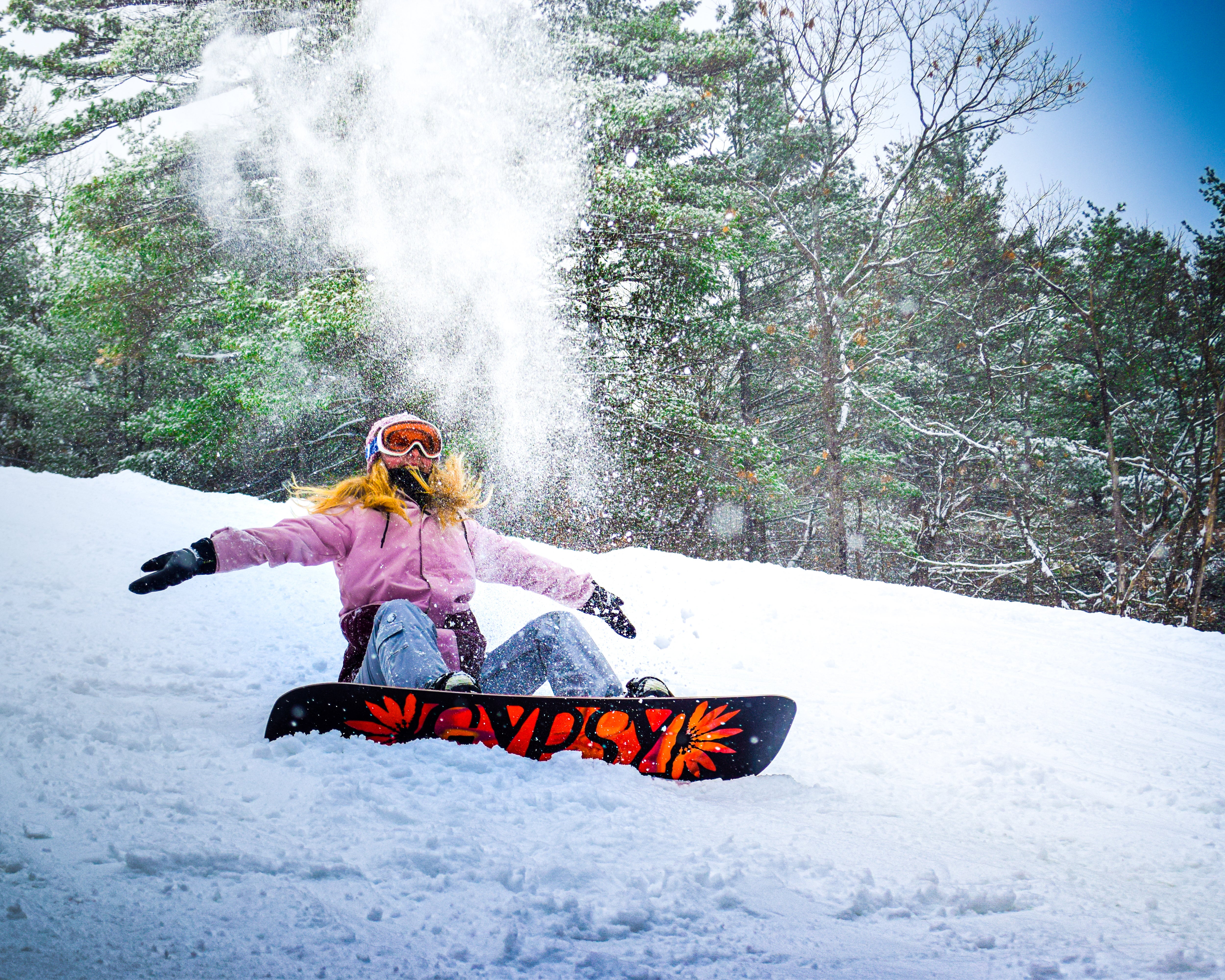 Woman throwing snow up in the air while taking break on slopes