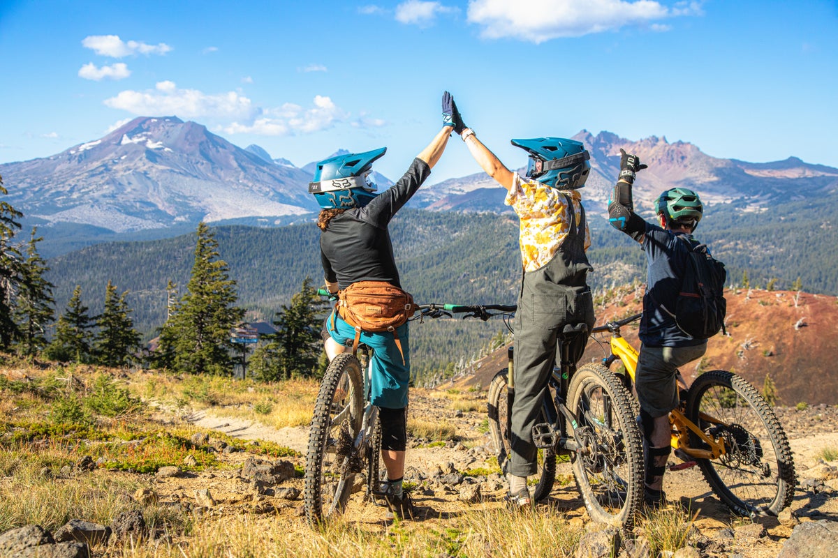 Friends on bikes celebrating at top of mountain biking trail
