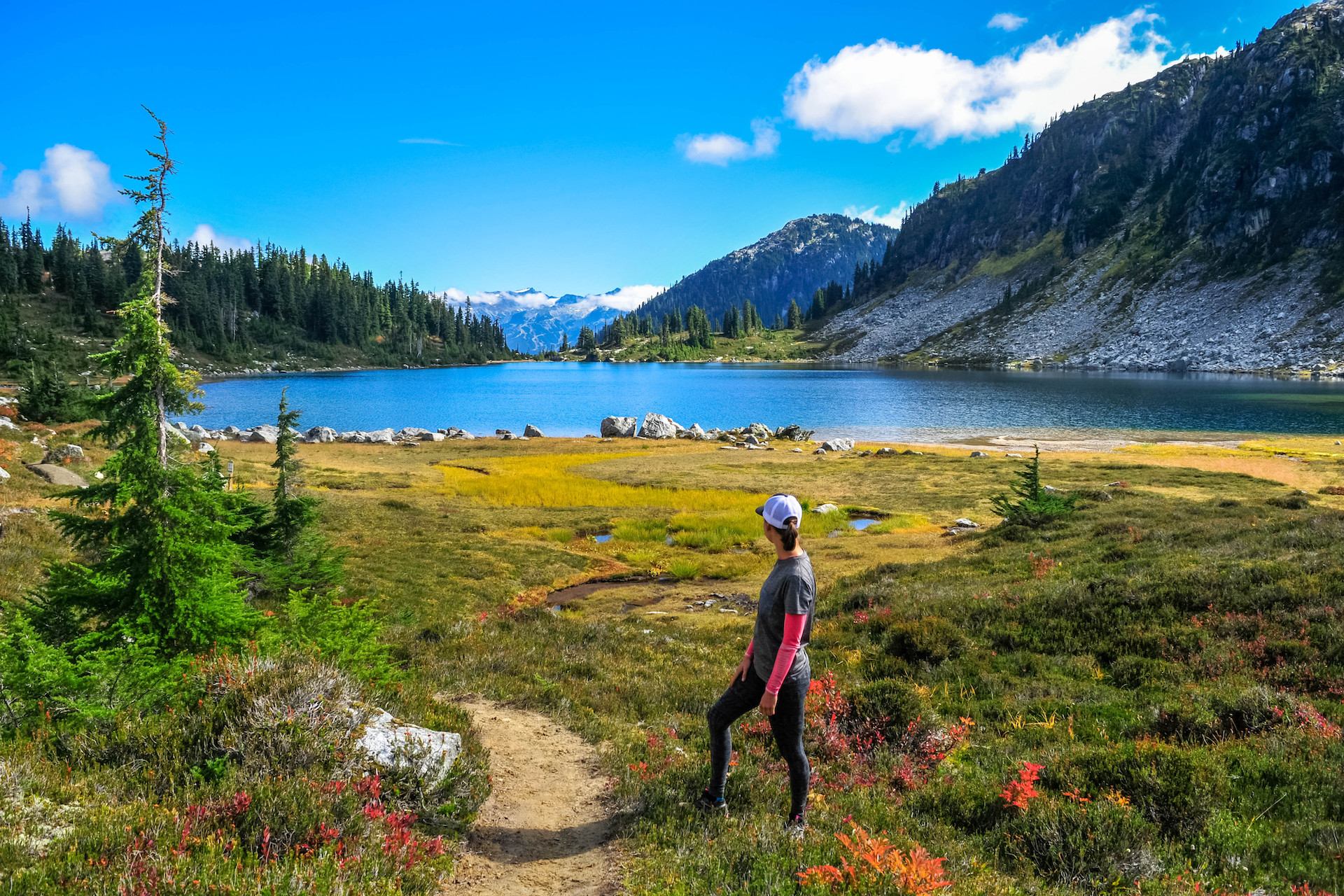 Person on hiking trail looking at view of lake and mountains
