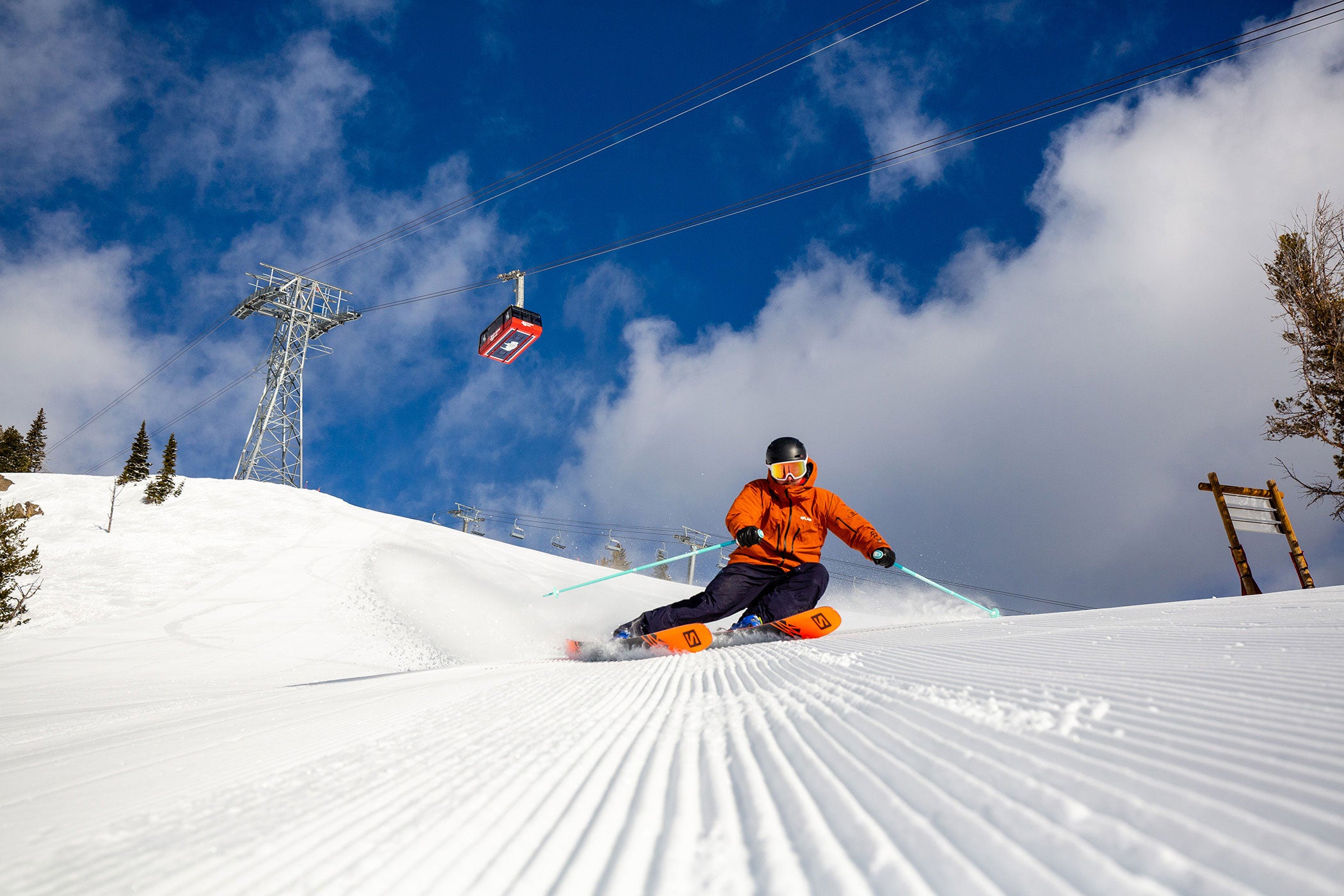 Person skiing beneath gondola on a sunny day on ski slopes