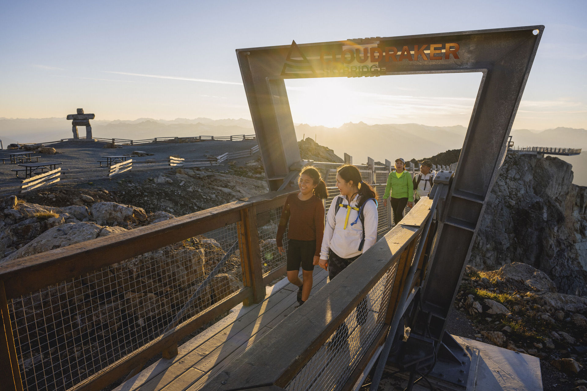 People walking over bridge high atop mountain on a sunny day