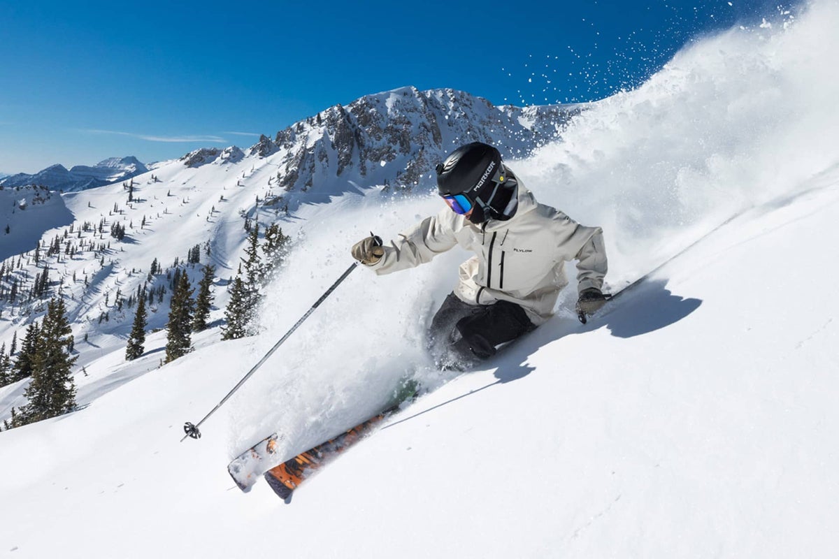 Skier skiing down Snowboard on a bluebird day to the backdrop of snow covered mountains