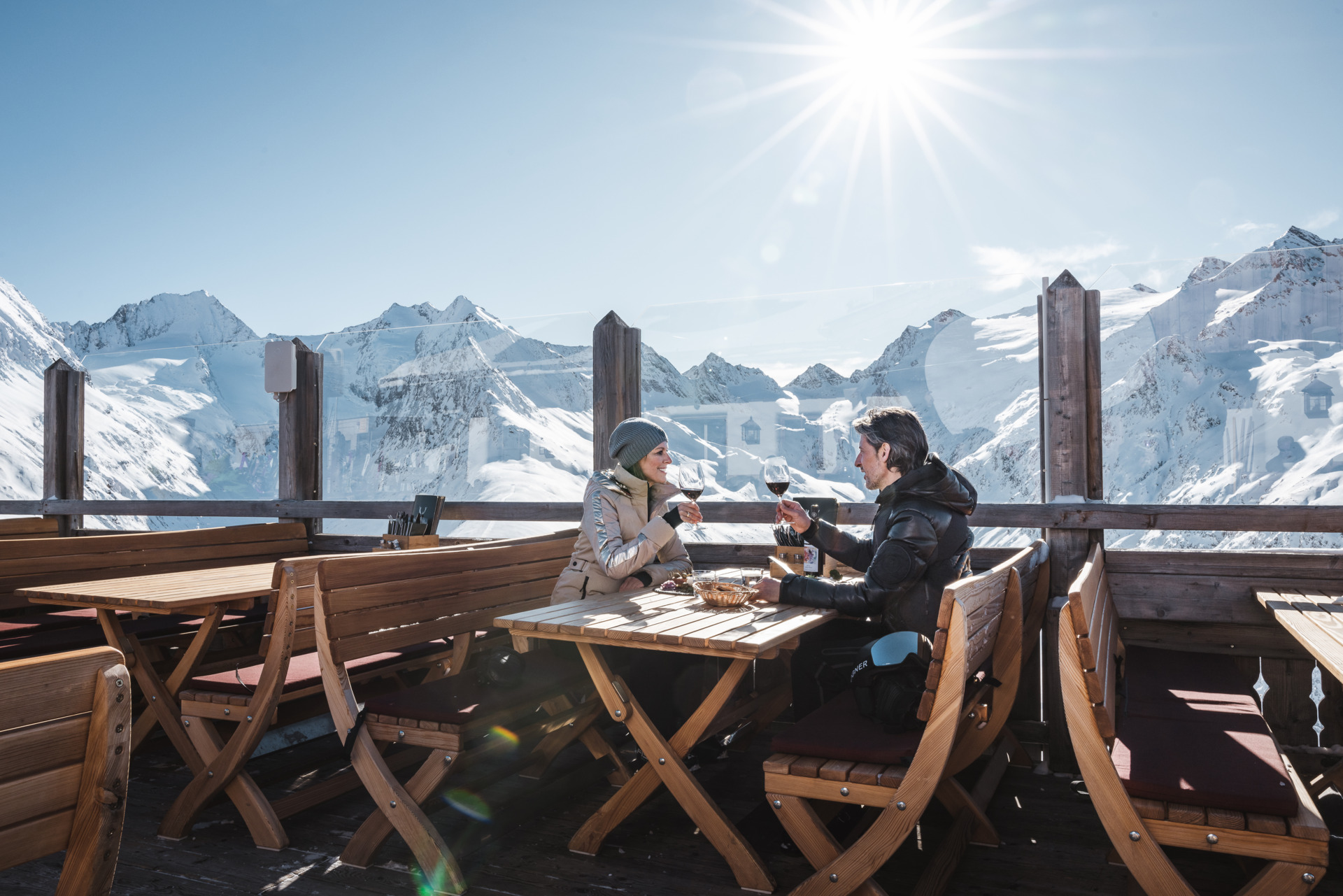 Een stel geniet van een maaltijd en drankjes op een zonnig terras met uitzicht op de met sneeuw bedekte bergen in het skigebied Obergurgl-Hochgurgl in Oostenrijk.