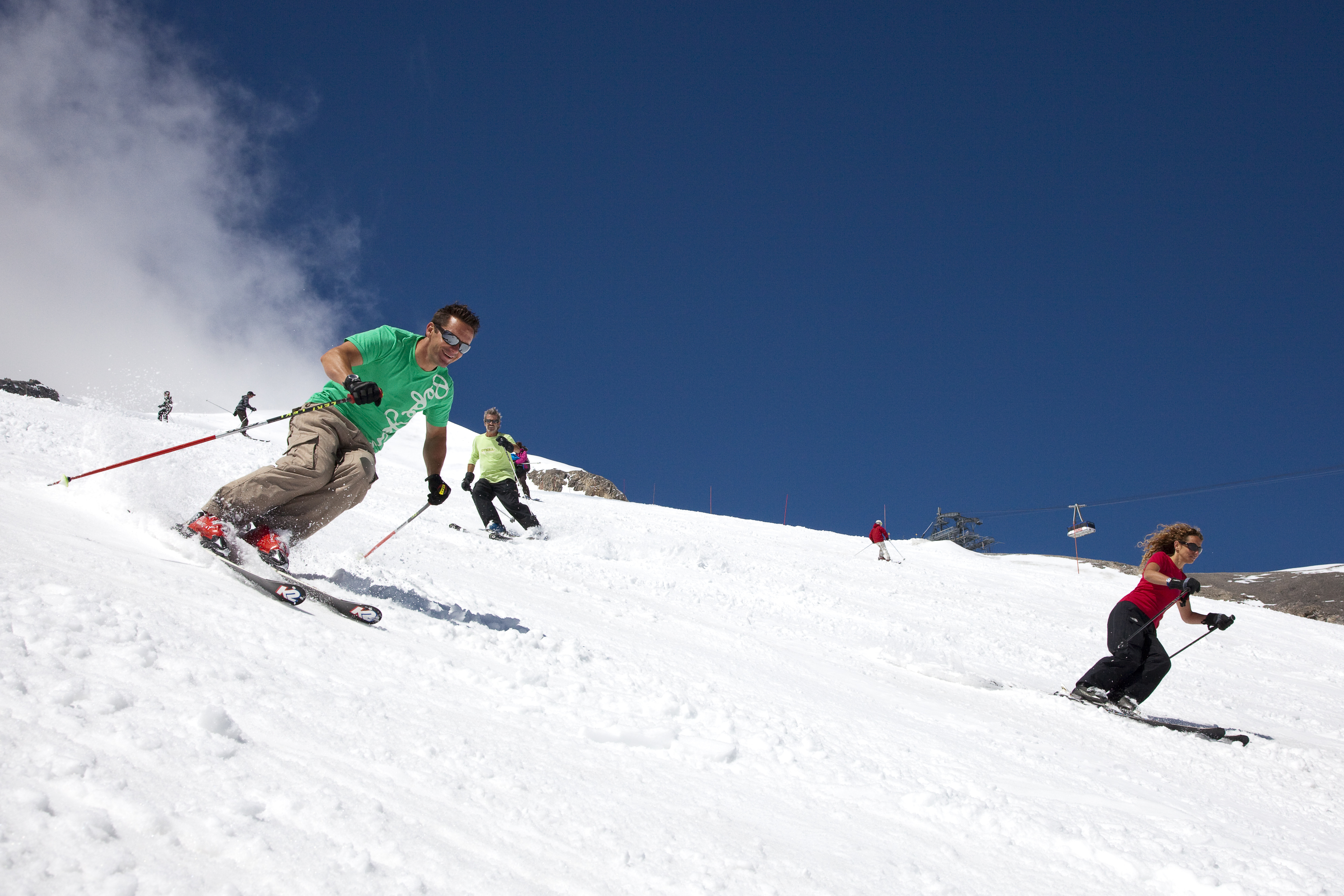 Group of skiers skiing down Tignes Ski Resort slopes on a warm sunny day