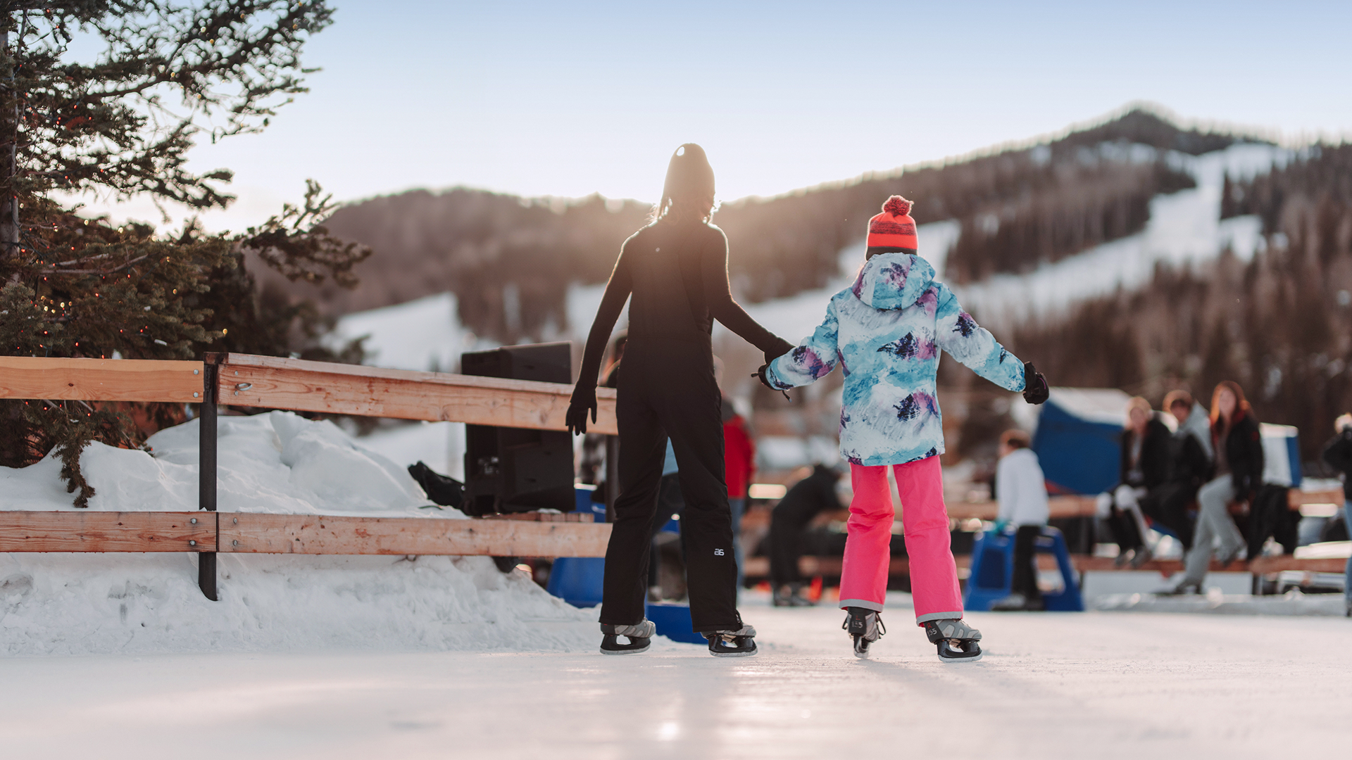 Two people holding hands while skating on outdoor ice rink