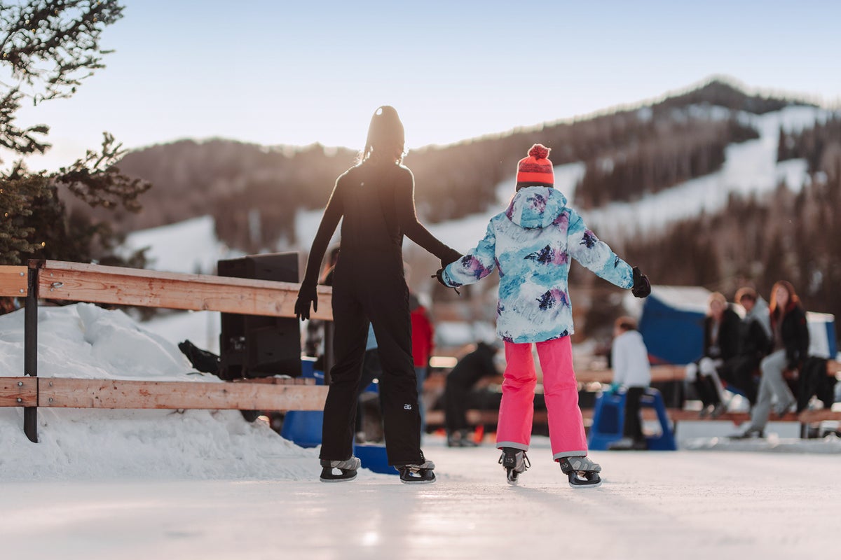 Two people holding hands while skating on outdoor ice rink
