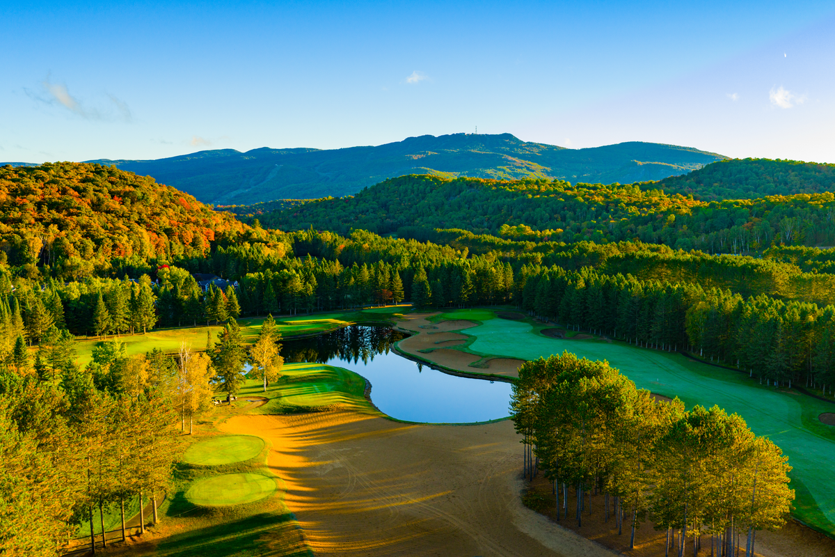 Aerial of golf course, pond, and rolling hills on a clear fall day
