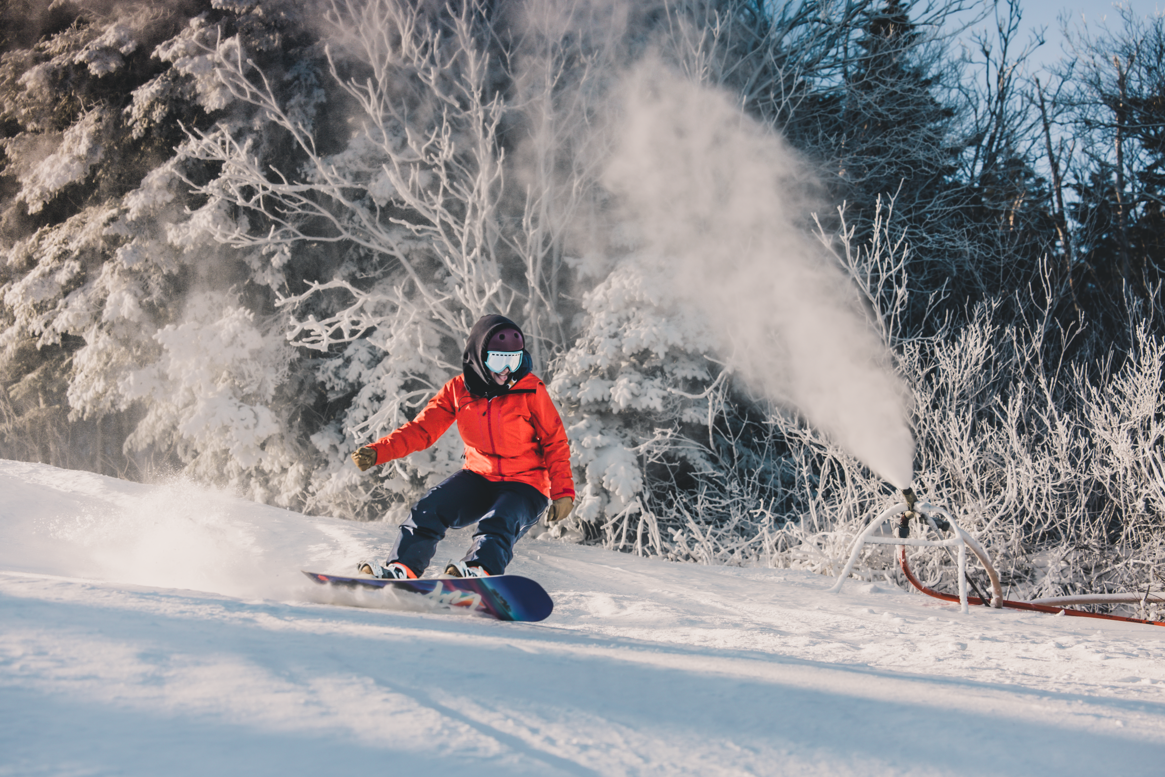 Snowboarder riding down slopes at Killington Ski Resort next to snow machine