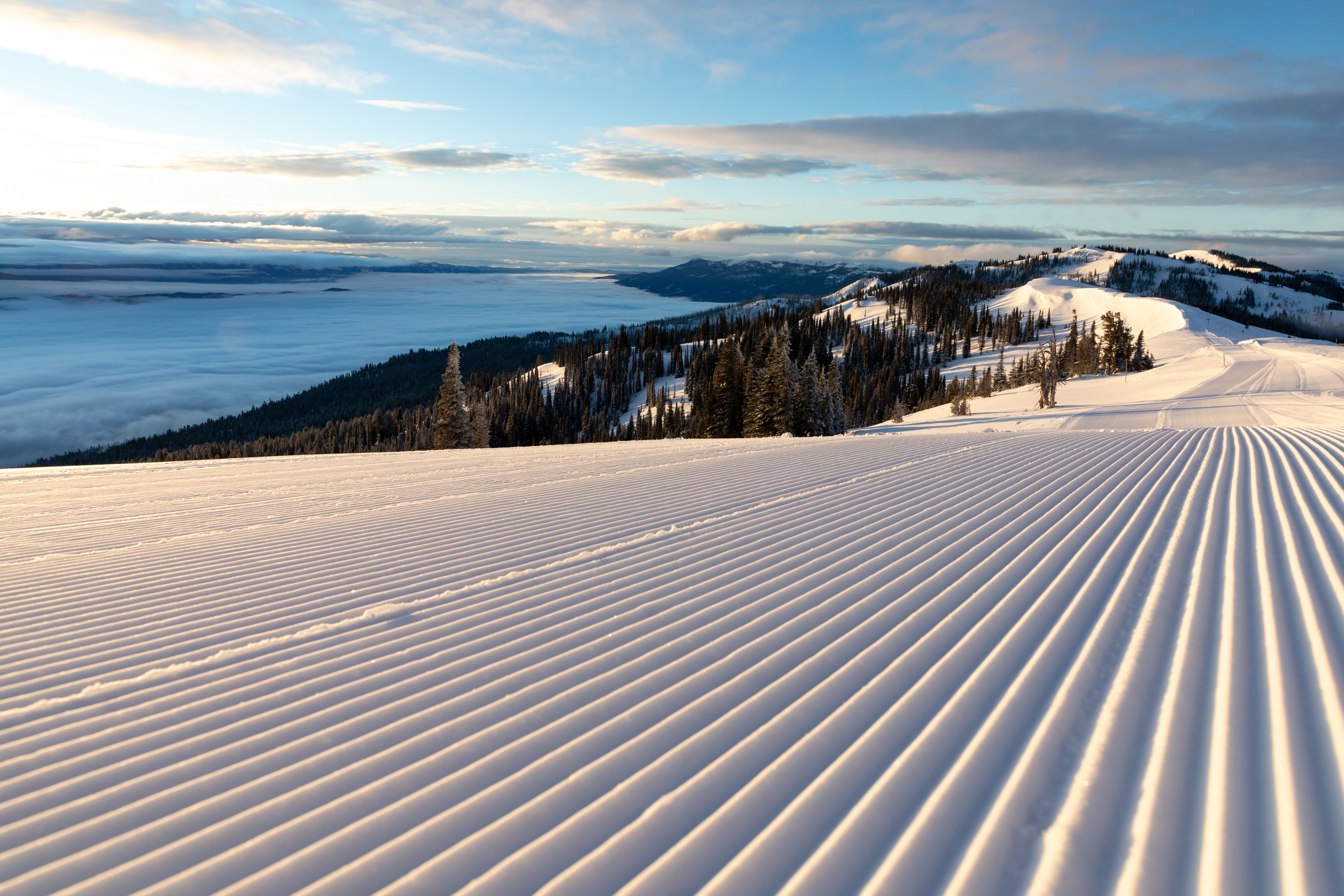 Perfectly groomed slopes of Tamarack Resort overlooking lake on a sunny day