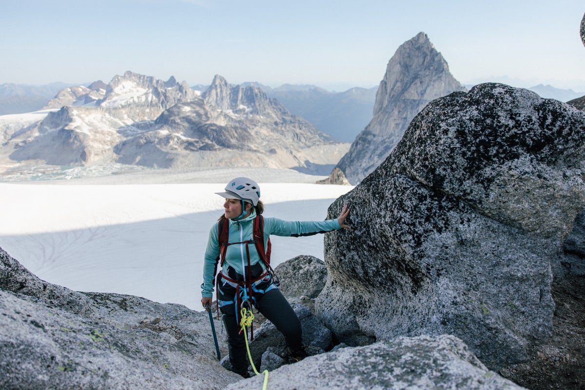 Woman taking break on via ferrata atop peak above icefield