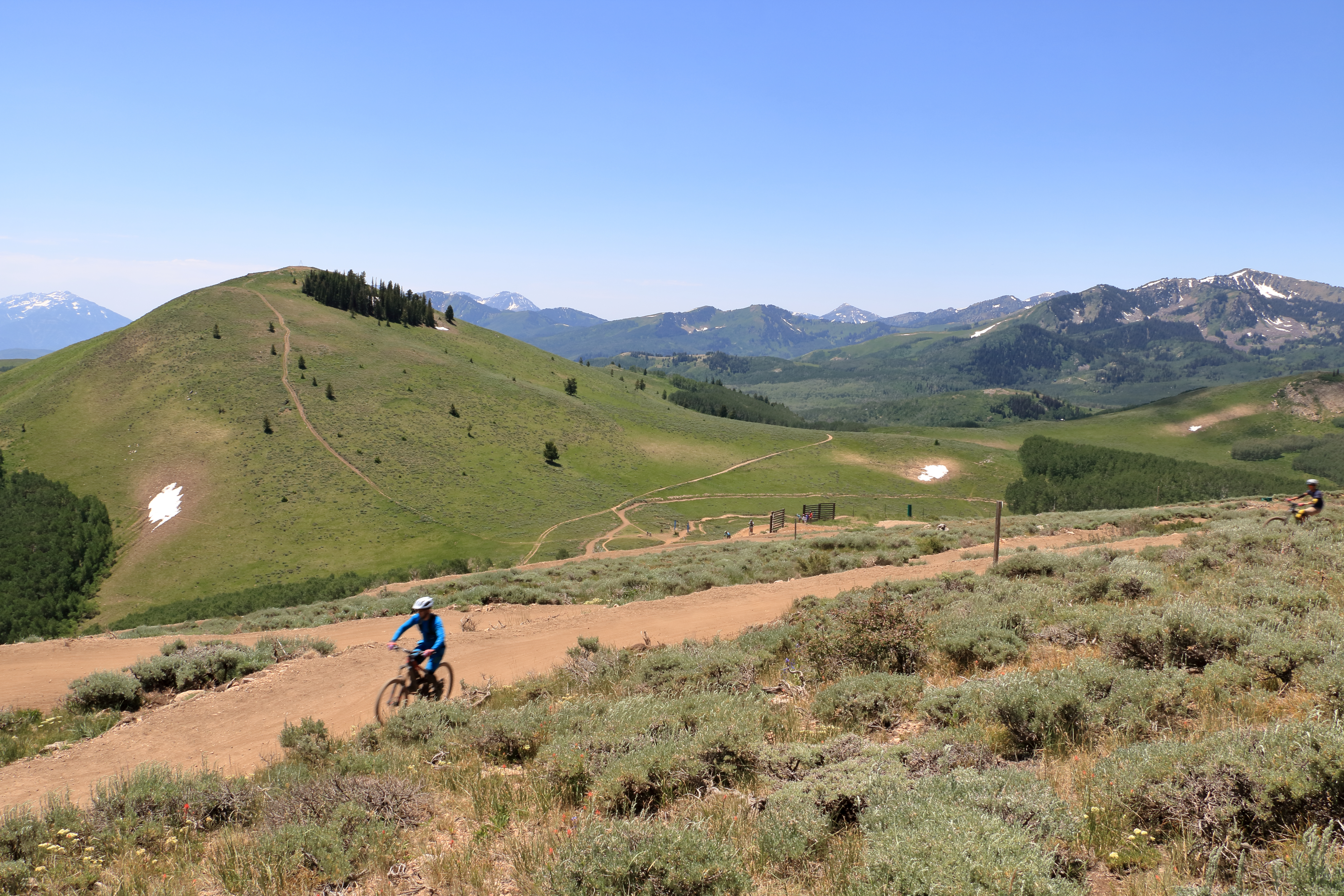Biking a dusty ski resort trail on a sunny day.