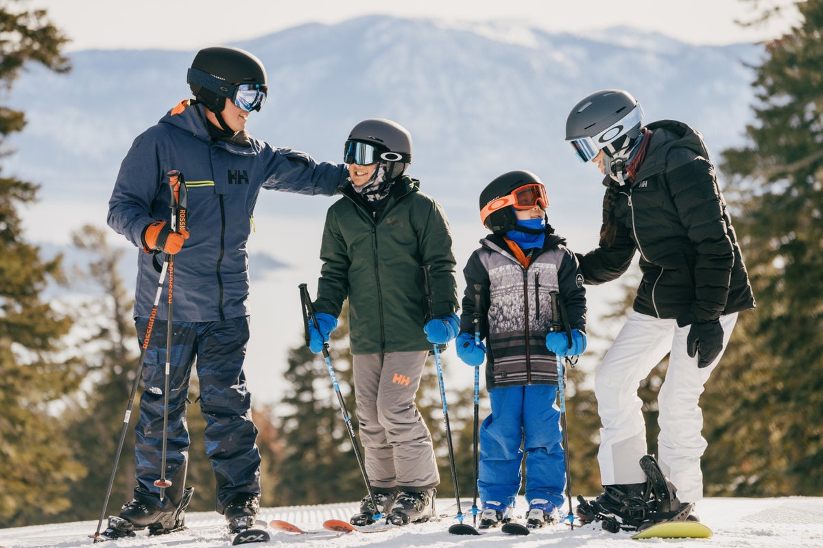 Family of skiers and snowboarders taking a break on groomed slopes