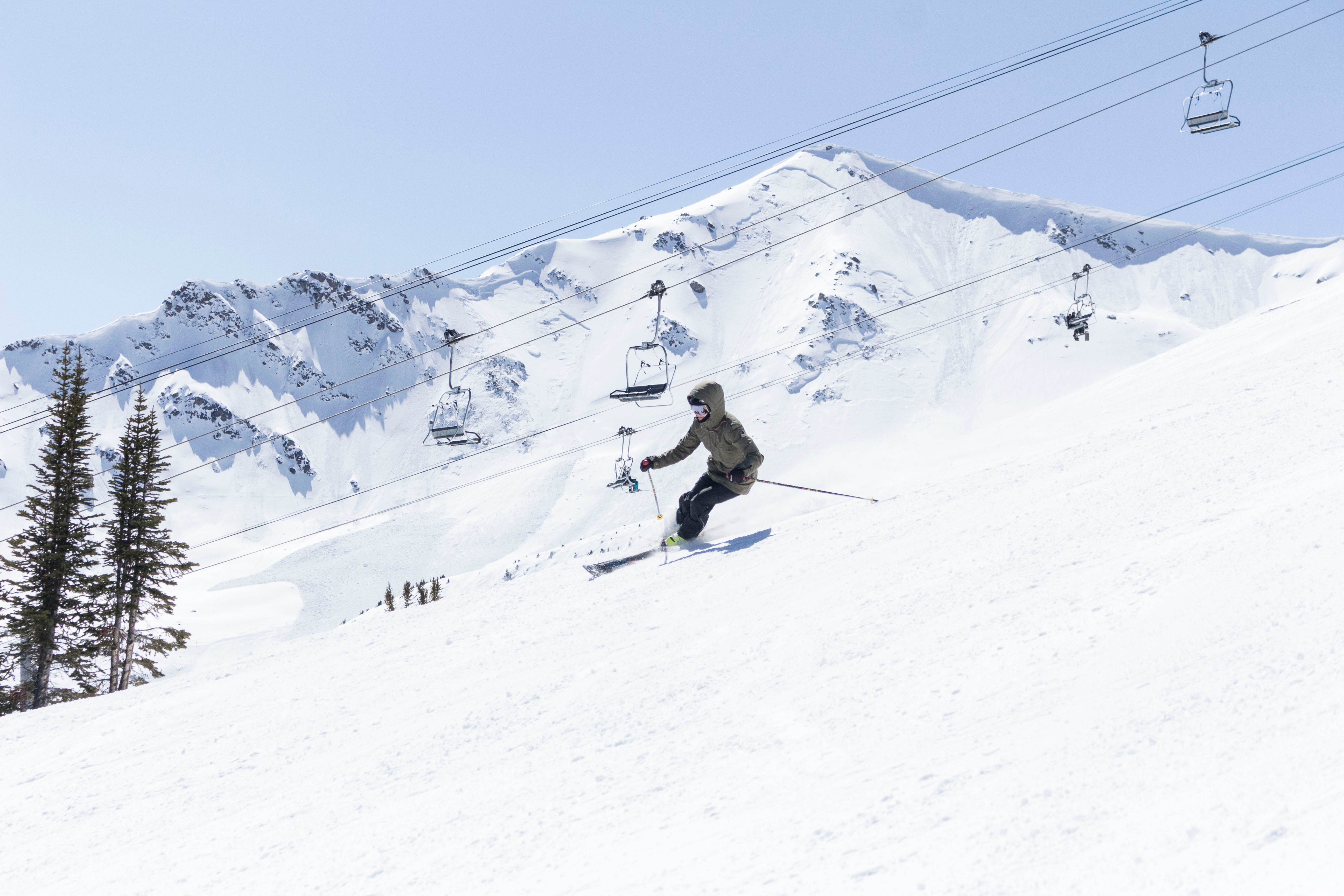 Skiing groomed run on a completely sunny day next to chairlifts