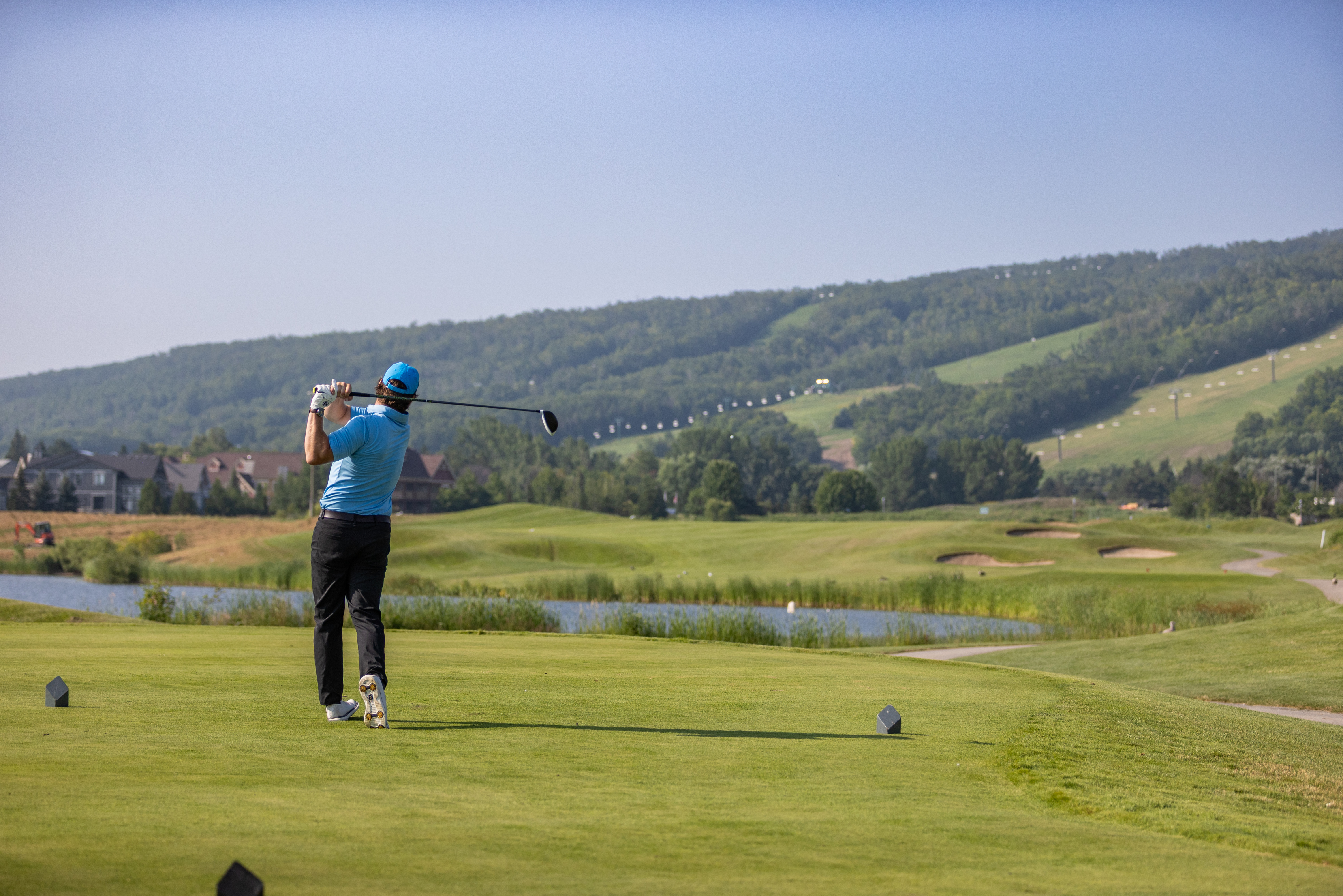 Man teeing off from tee box of golf course on a sunny day