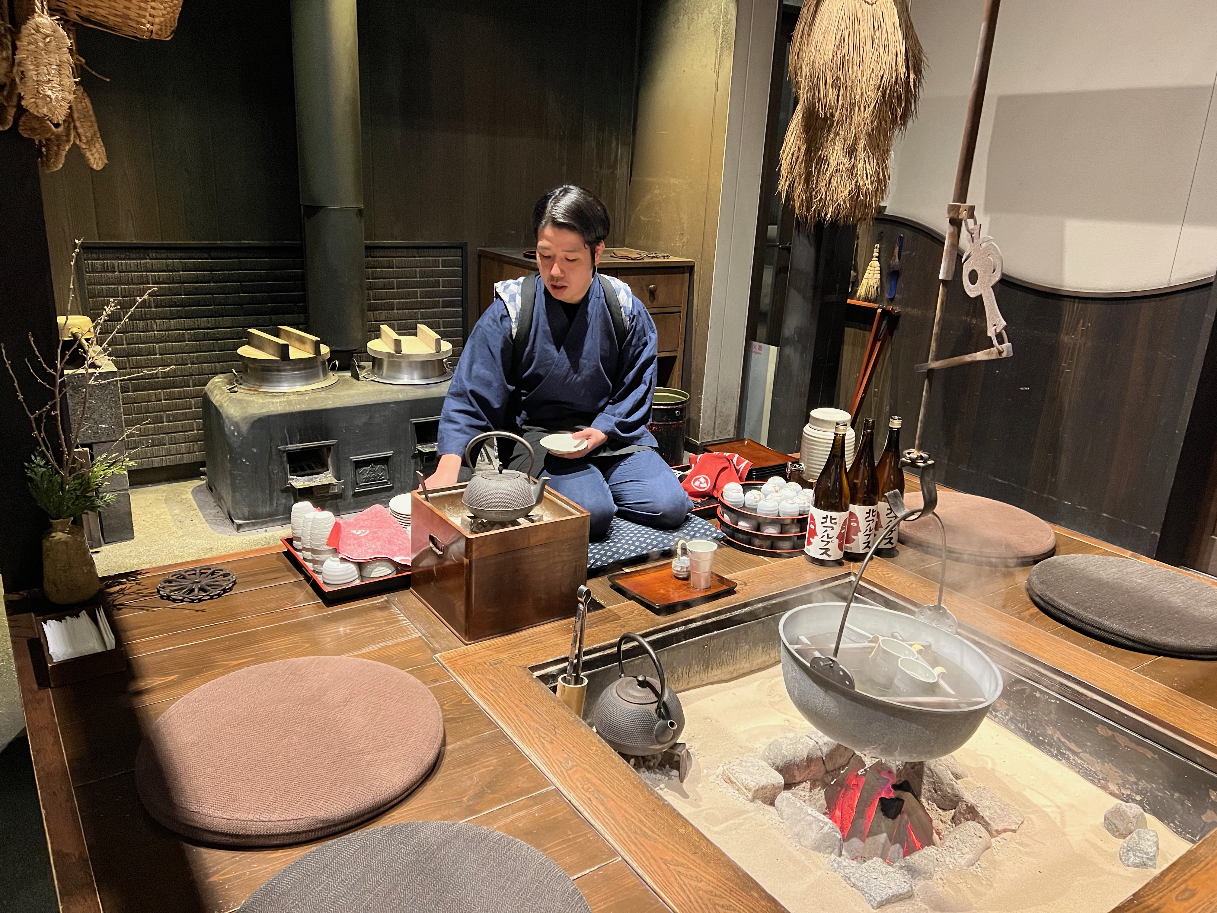 Person enjoying hot Japanese sake warming by fire at Hoshino Resorts KAI Alps
