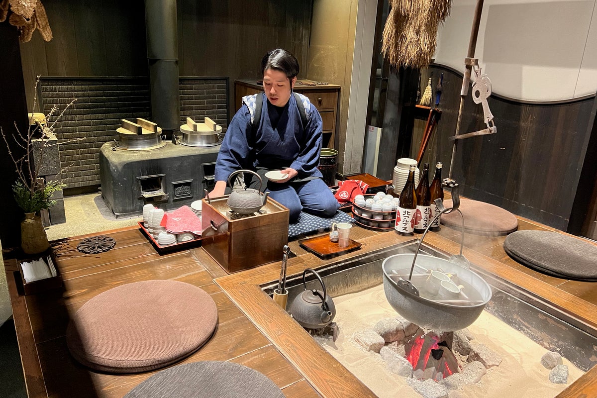 Person enjoying hot Japanese sake warming by fire at Hoshino Resorts KAI Alps