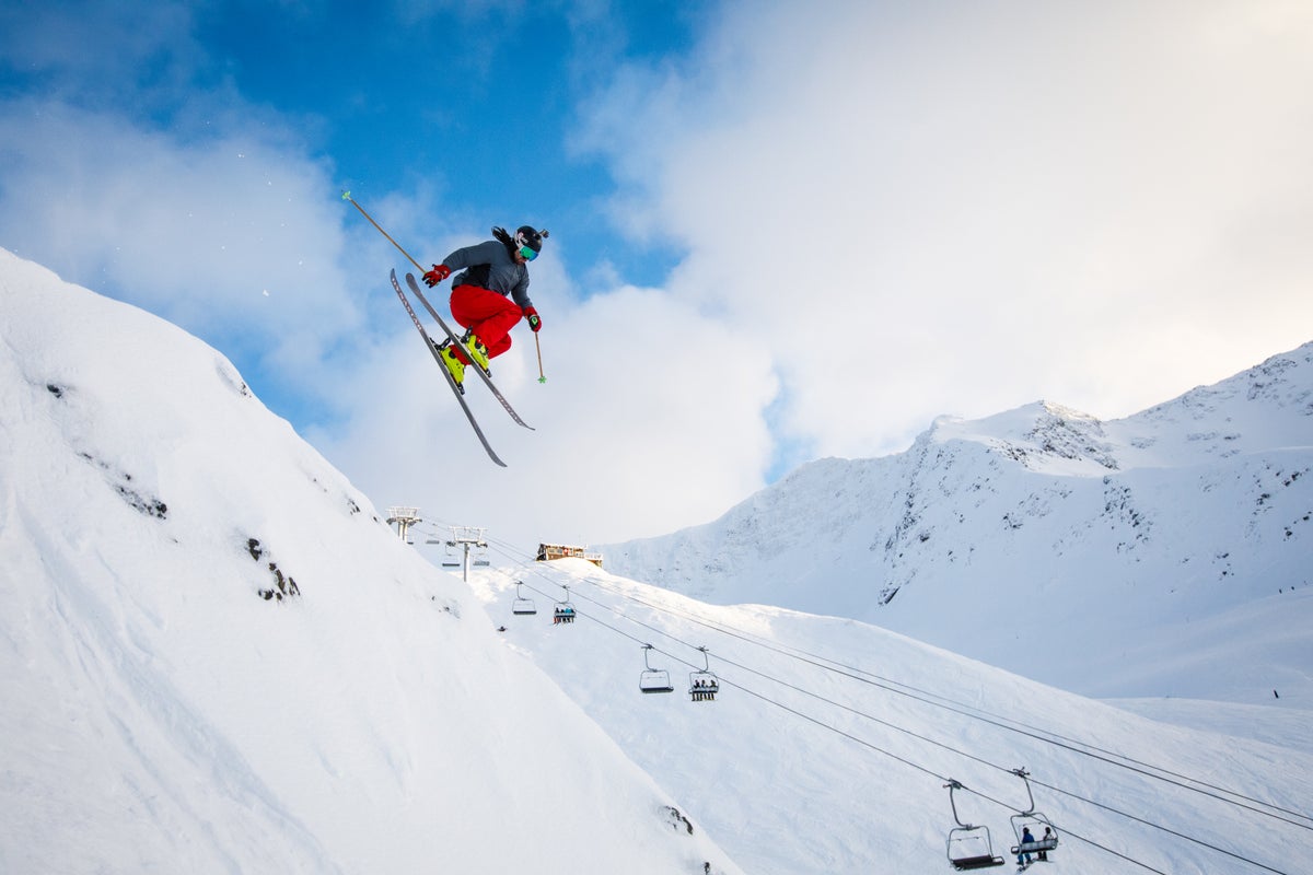 Person skiing down Alyeska Ski resort with snow-covered mountains behind them