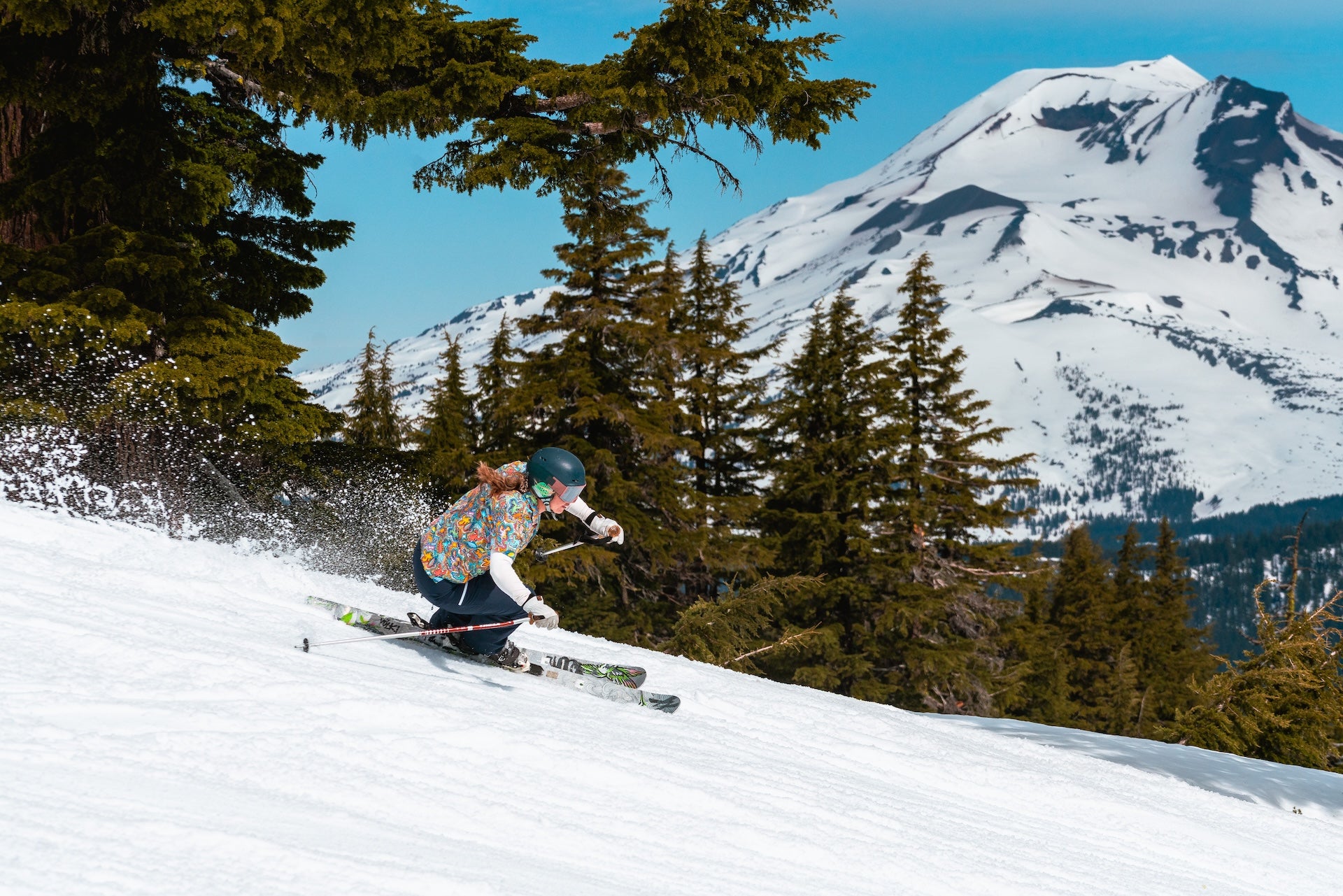 Skiing in a bright shirt skiing down ski run on a sunny spring day