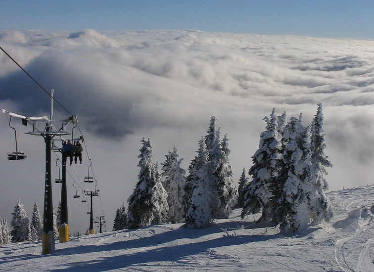 People riding chairlift above the clouds