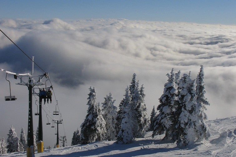 People riding chairlift above the clouds