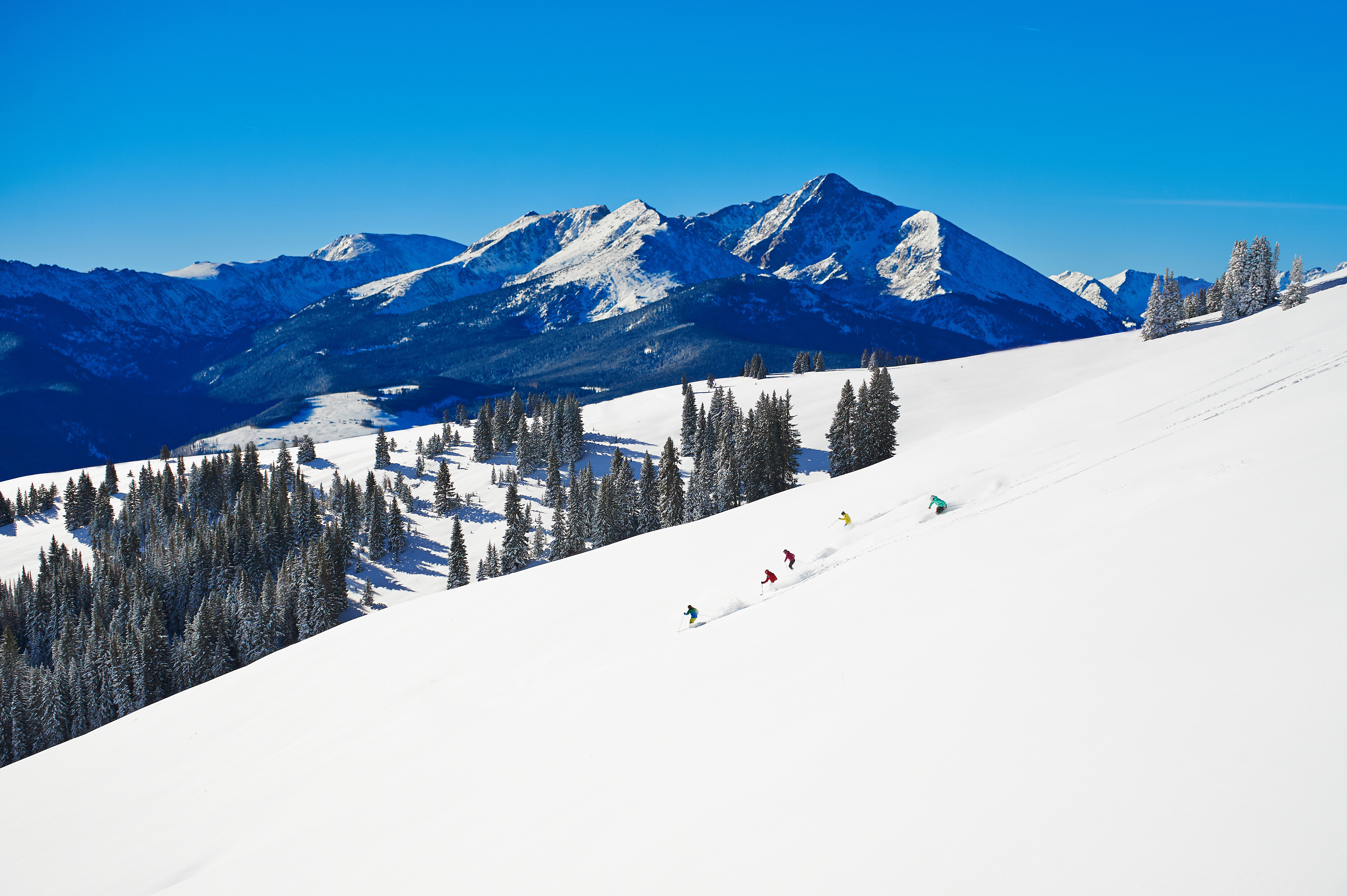 Group of skiers ripping through powder on a bluebird day