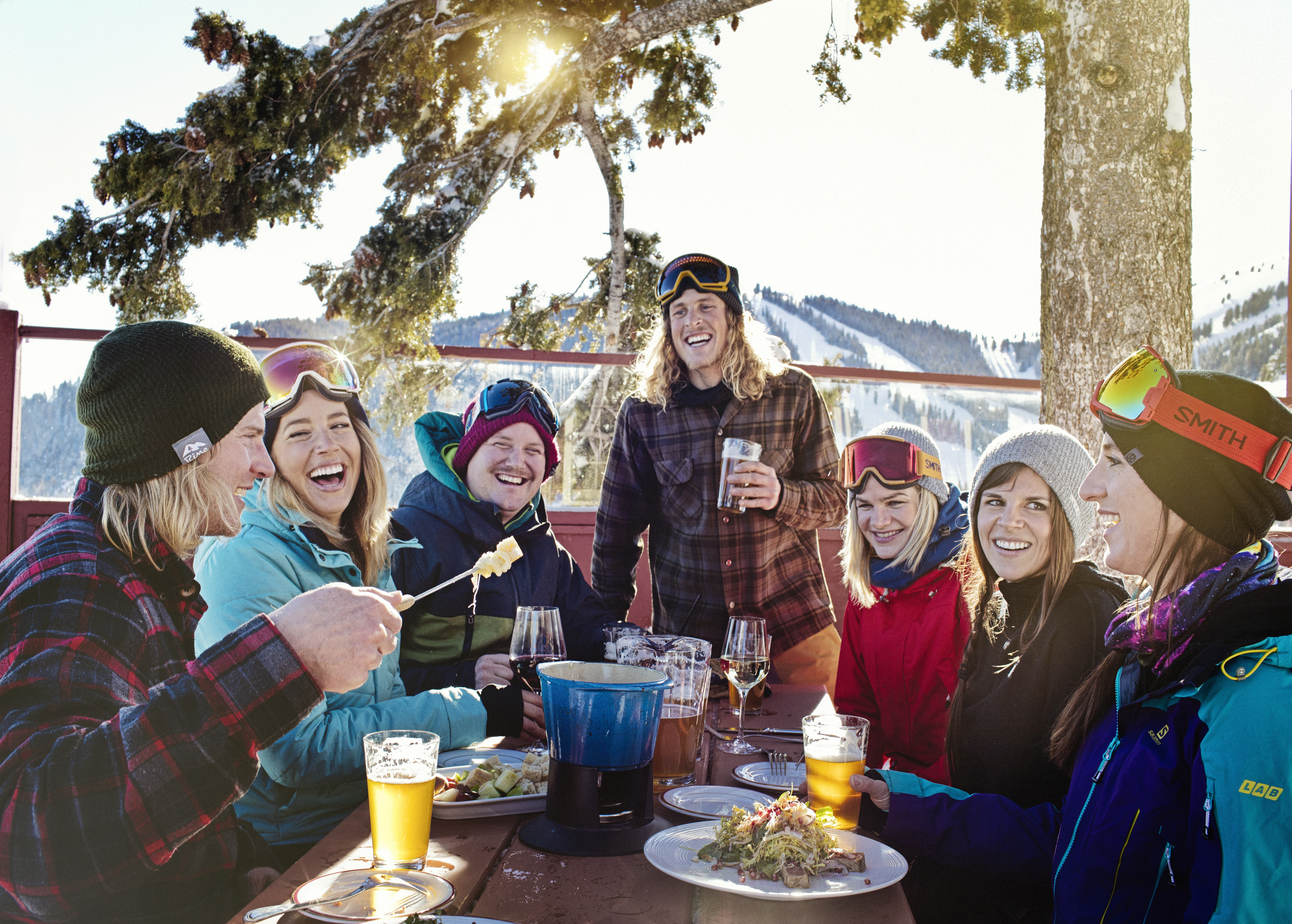 Friends enjoying a meal at Sun Valley Resort's Roundhouse Restaurant in Winter with the snow-covered mountains in the background