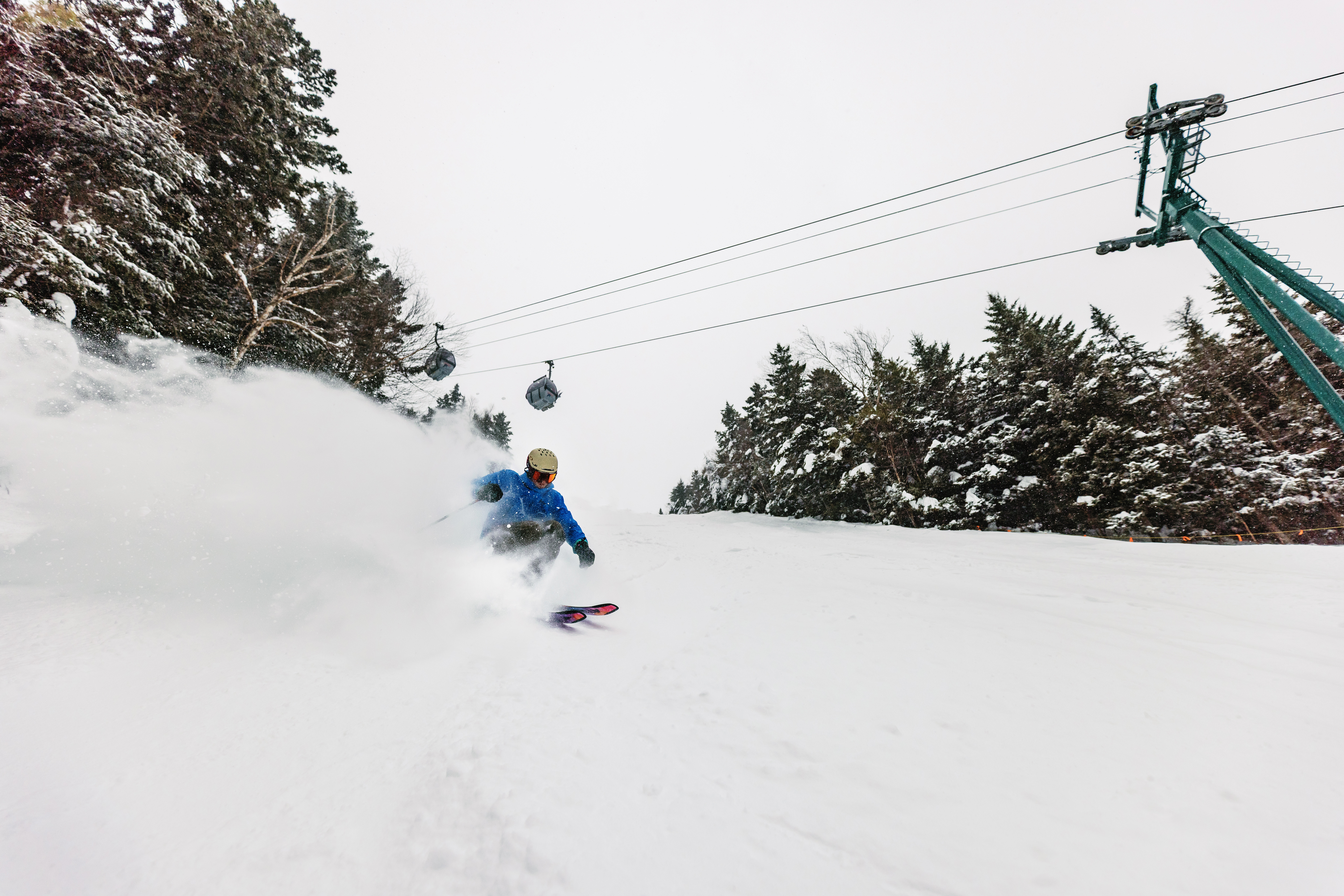 Skiing beneath gondola at Loon Mountain on a cloudy, snowy day