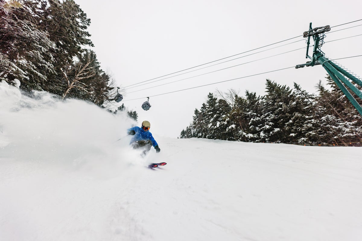 Skiing beneath gondola at Loon Mountain on a cloudy, snowy day
