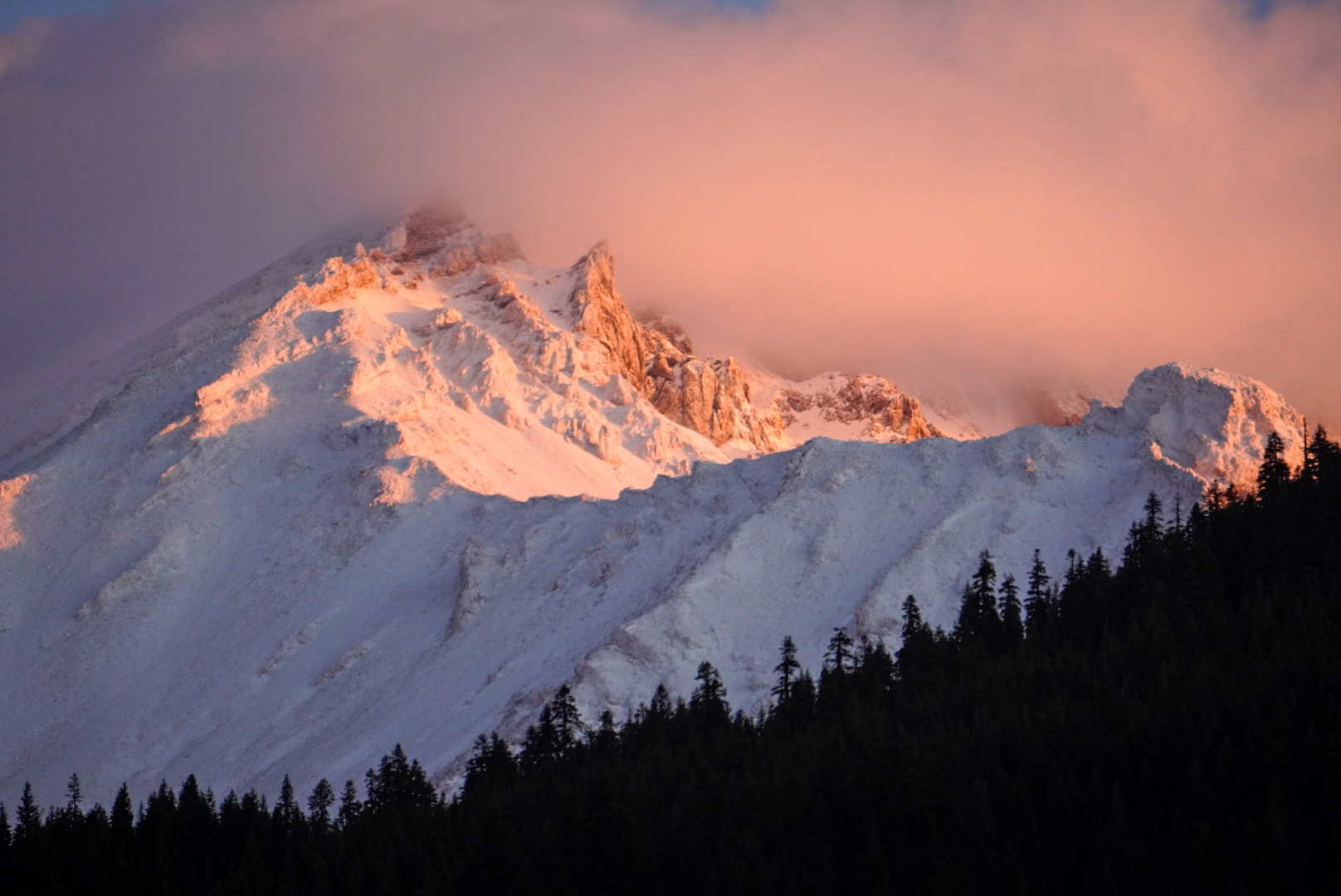 Fog and clouds linger over the top of snow-covered Mt. Shasta