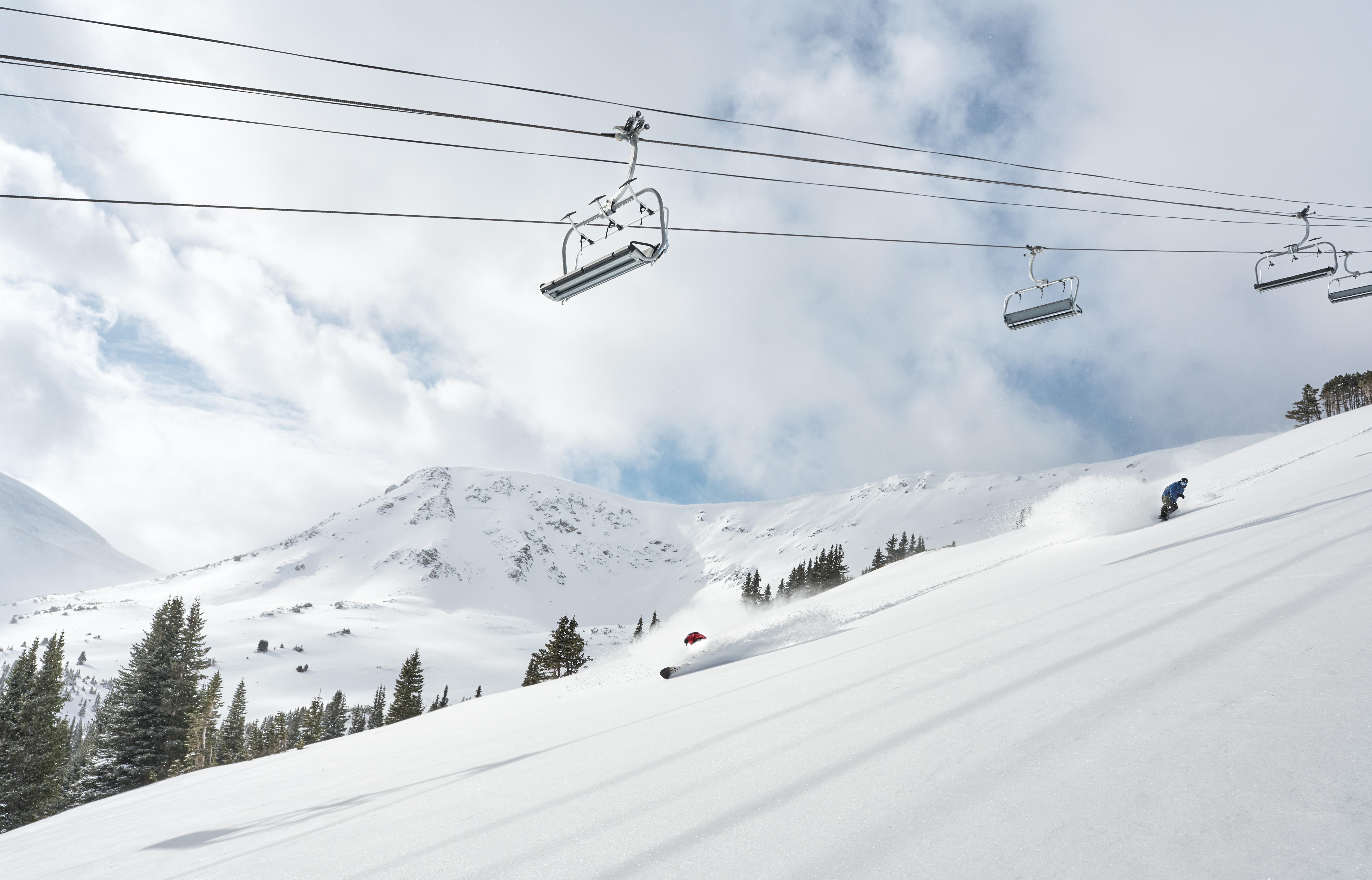 Skiing through powder below chairlift
