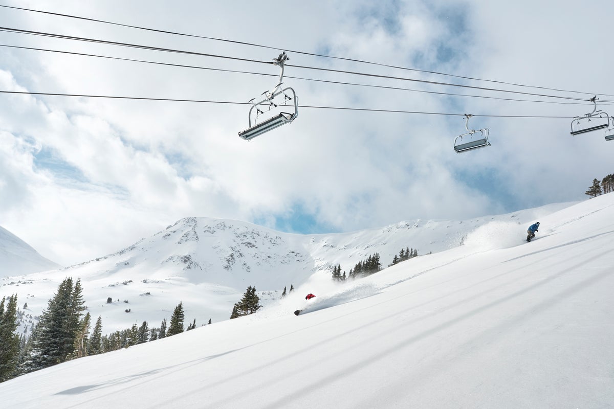 Skiing through powder below chairlift