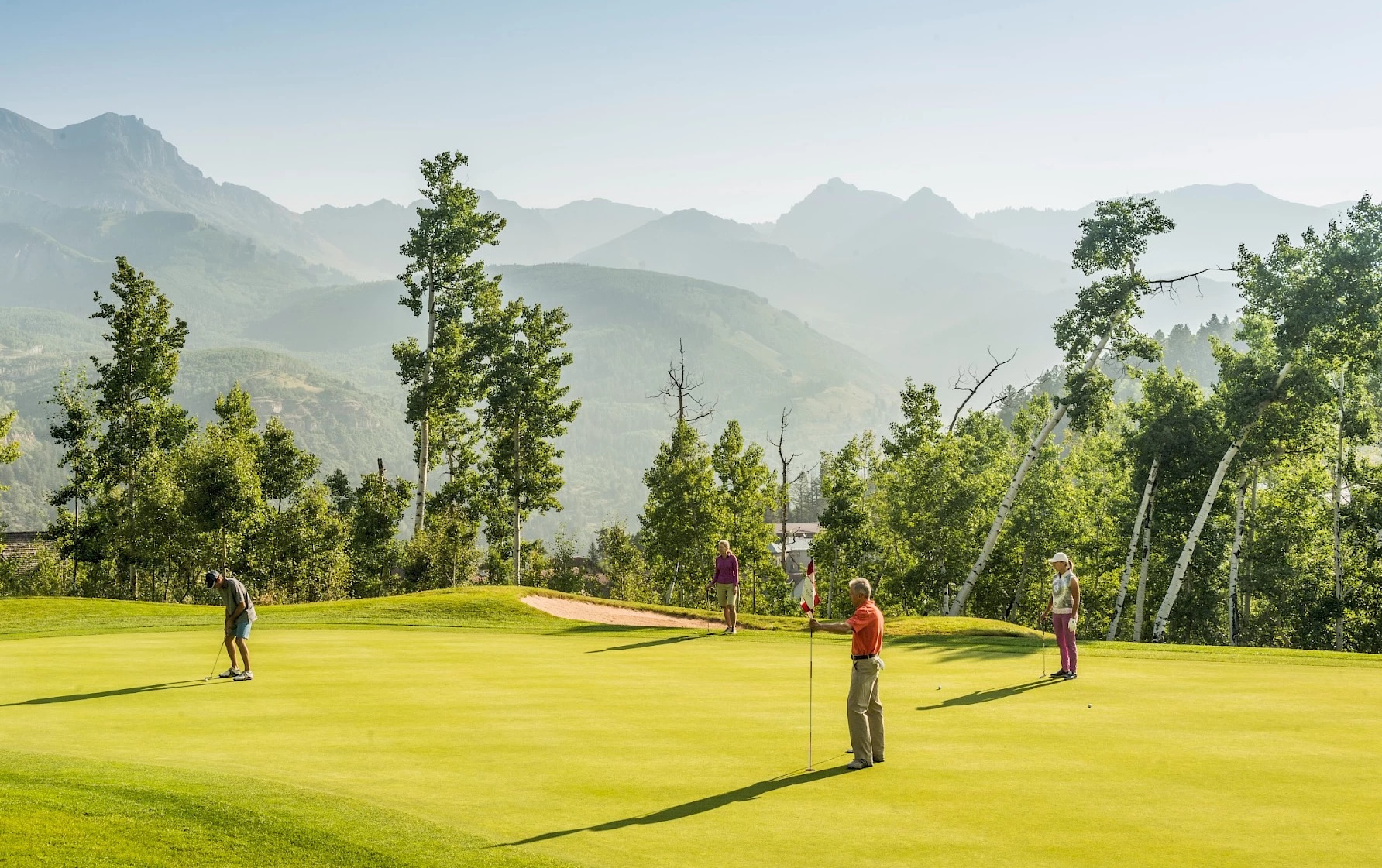 Group of putting watching someone putt on green at Telluride Golf Course in Colorado.