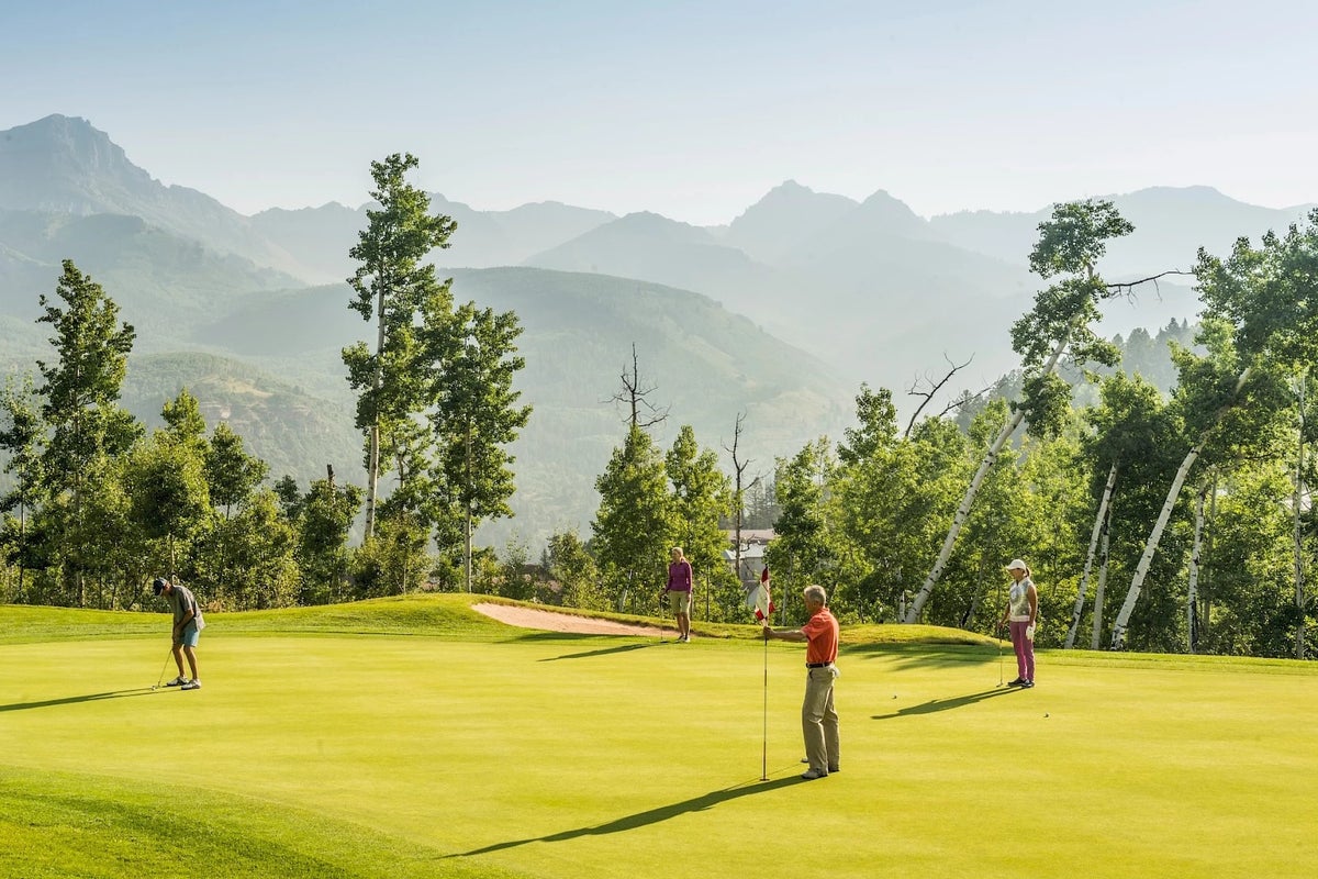 Group of putting watching someone putt on green at Telluride Golf Course in Colorado.
