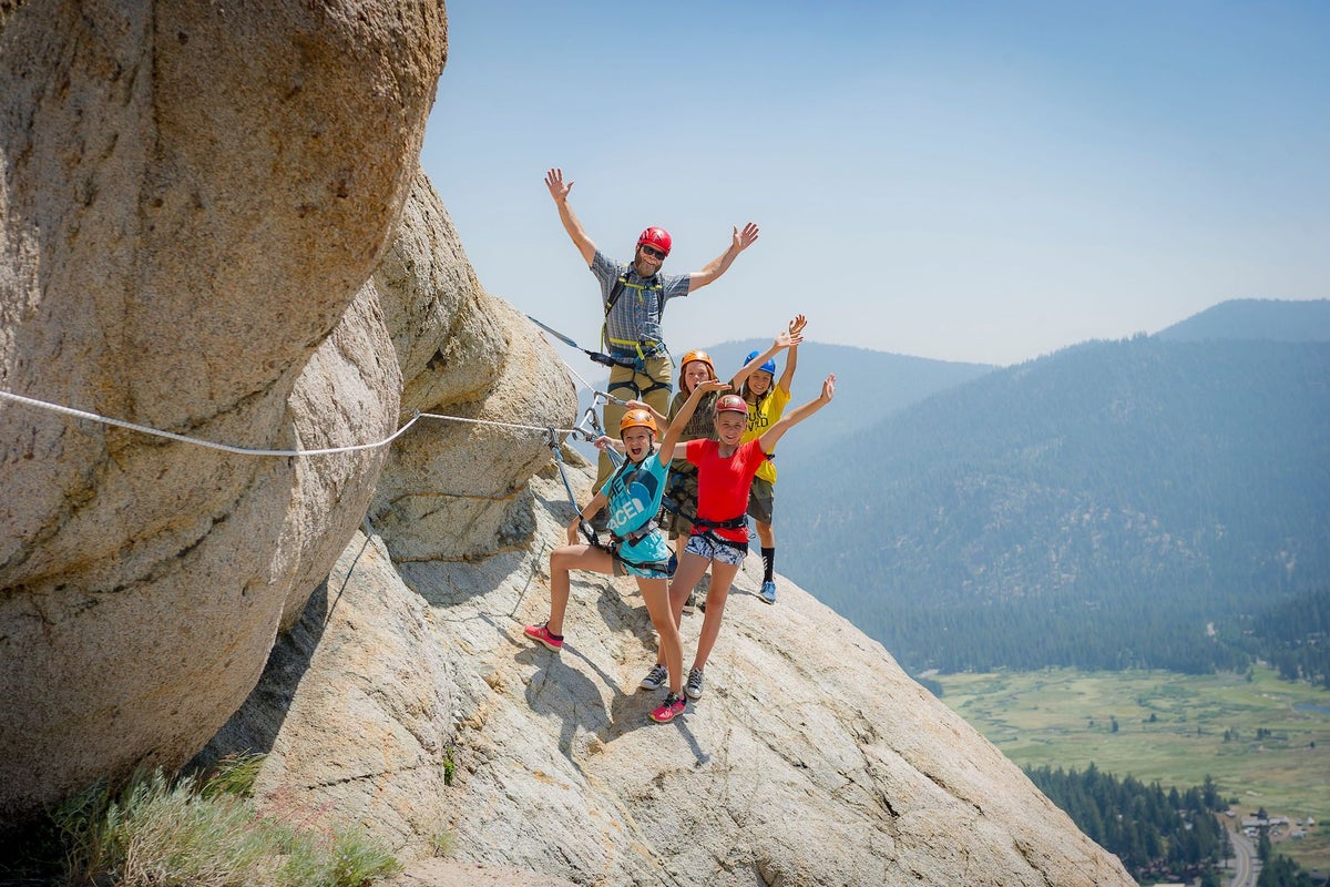 Family hanging from Via Ferrata on a sunny summer day