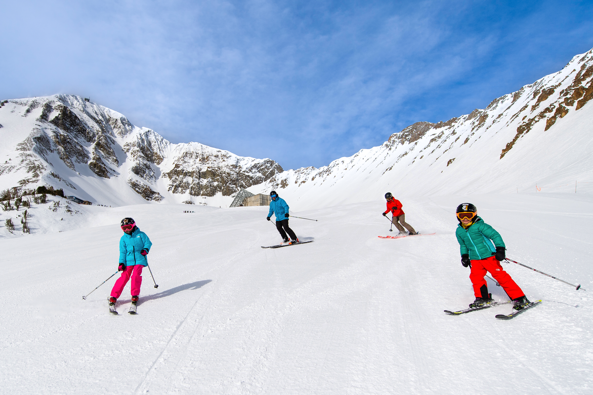 Family skiing down groomed slope on a sunny day at Big Sky in Montana