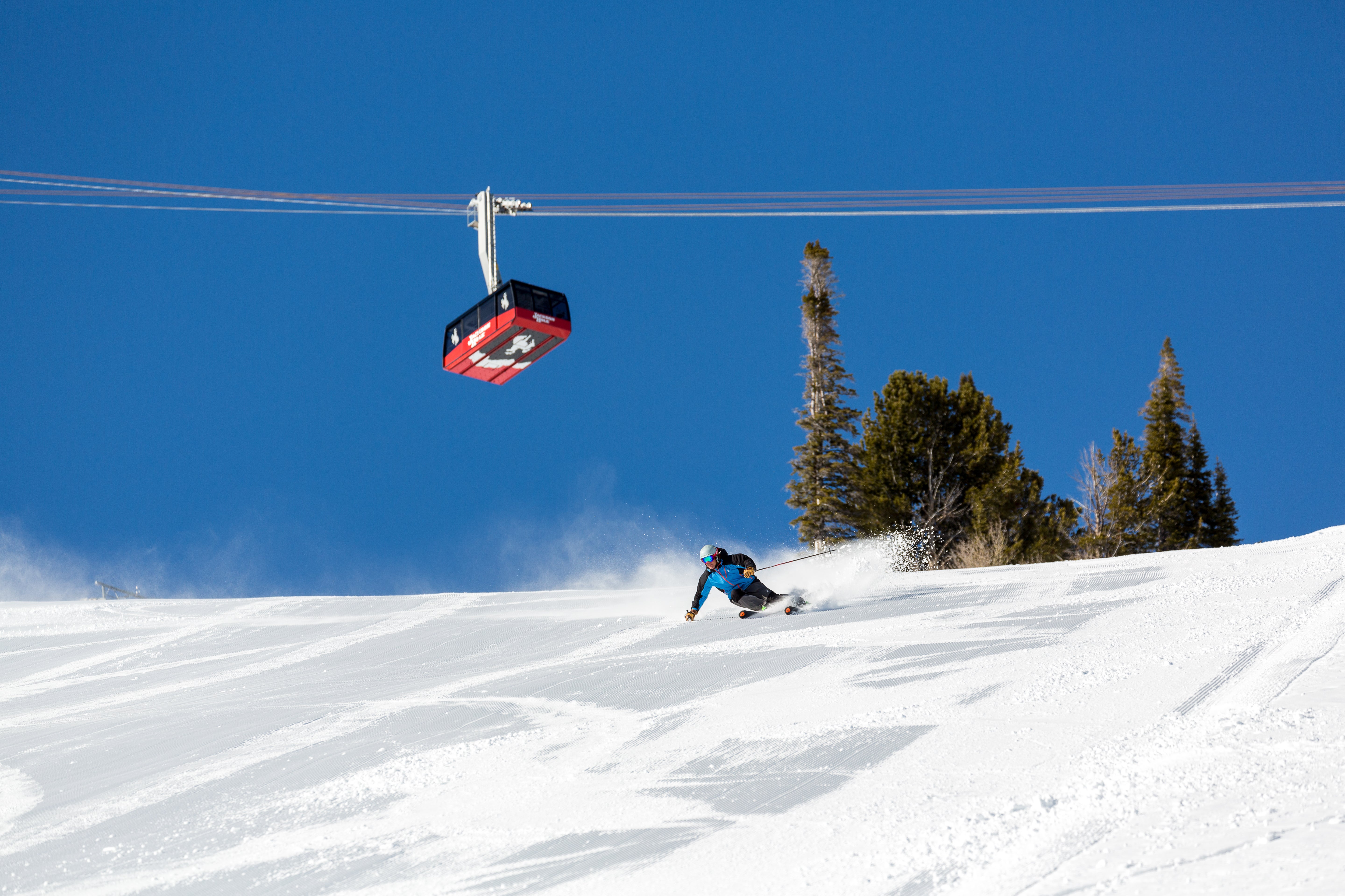 Skiing down groomed run beneath gondola