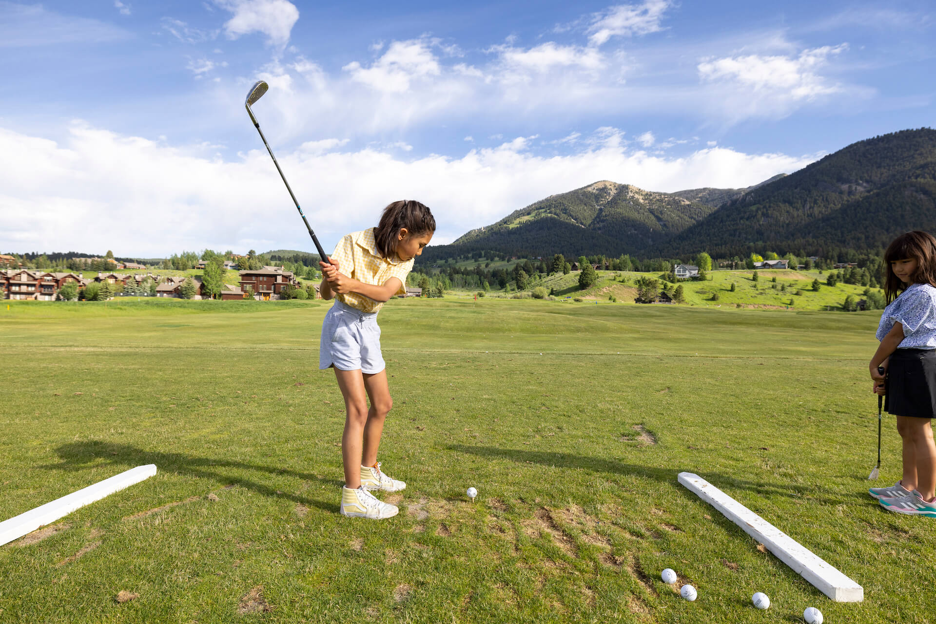 Kid swinging golf clubs at golf range at Big Sky