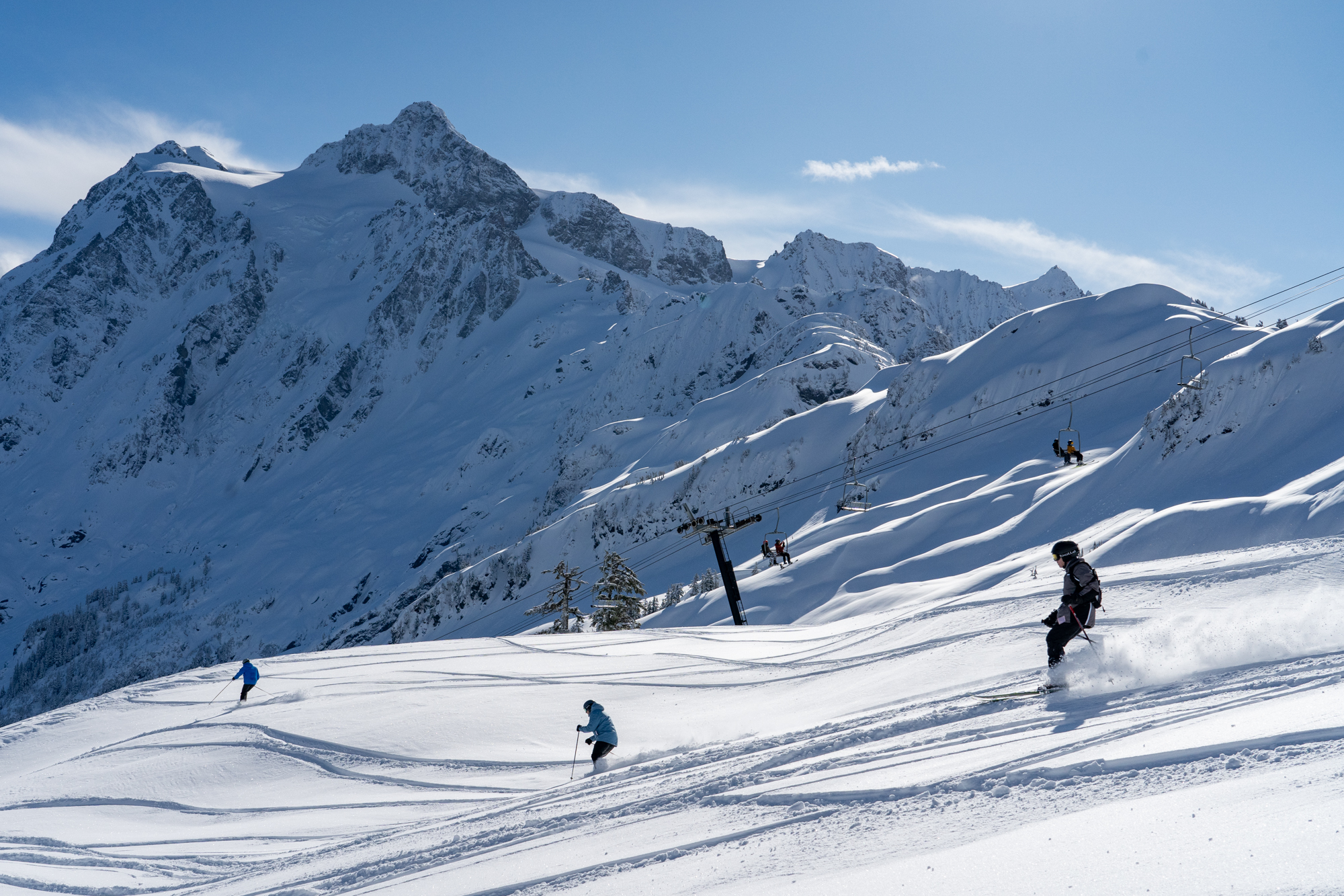Different skiers skiing through powder on a bluebird day at Mt. Baker
