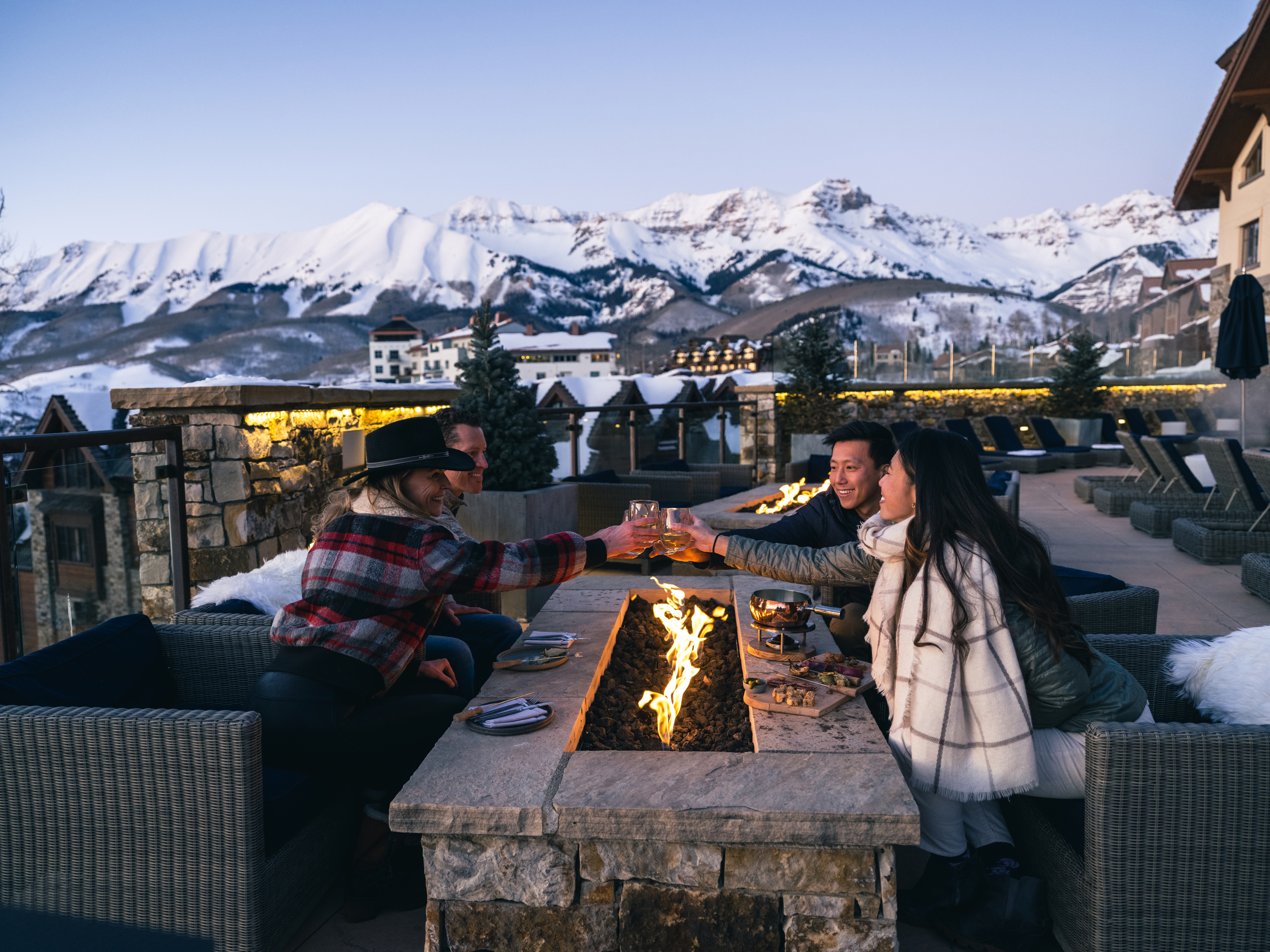 Friends toasting glasses fireside after sunset