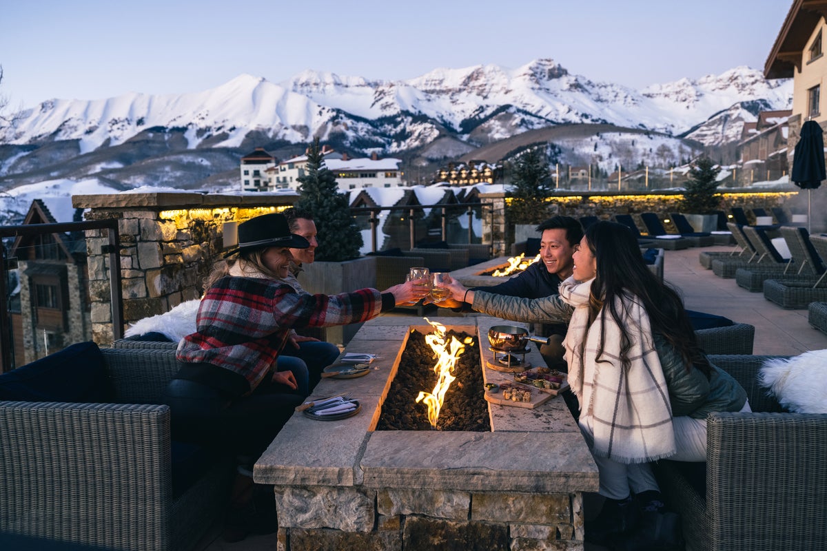 Friends toasting glasses fireside after sunset