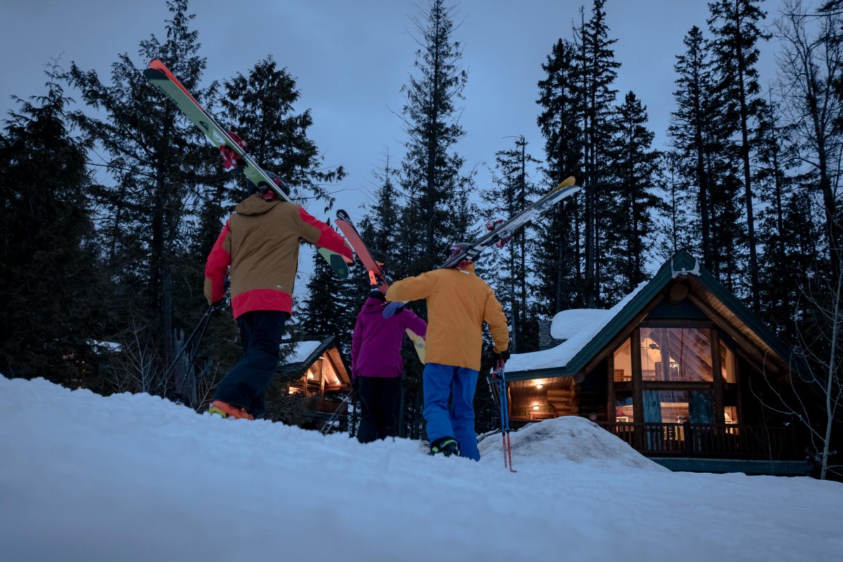 Group of people walking toward accommodations in the snow with skis